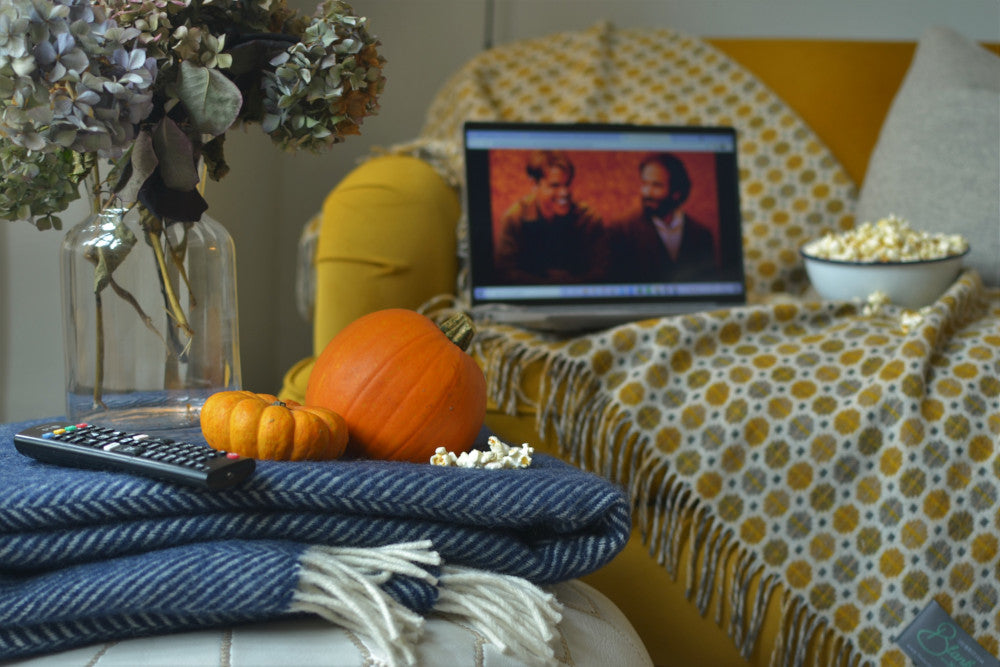 Laptop sits on top of a wool British made blanket with a movie playing for a cosy night