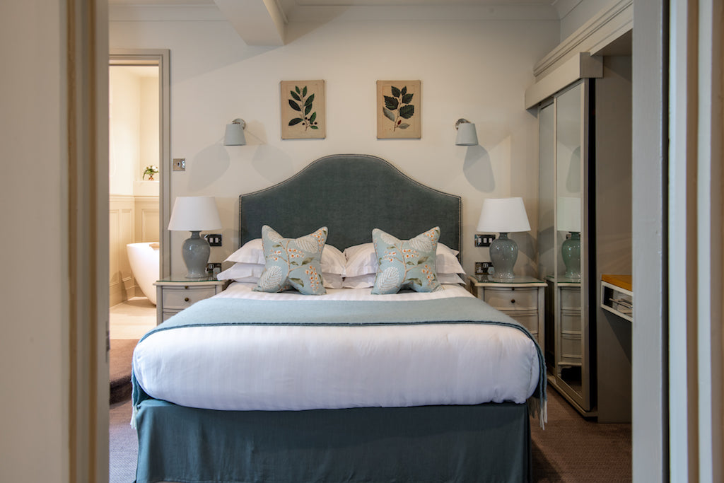 Bedroom interior featuring a neatly made bed with pillows, flanked by two lamps on nightstands, creating a cozy and inviting atmosphere.