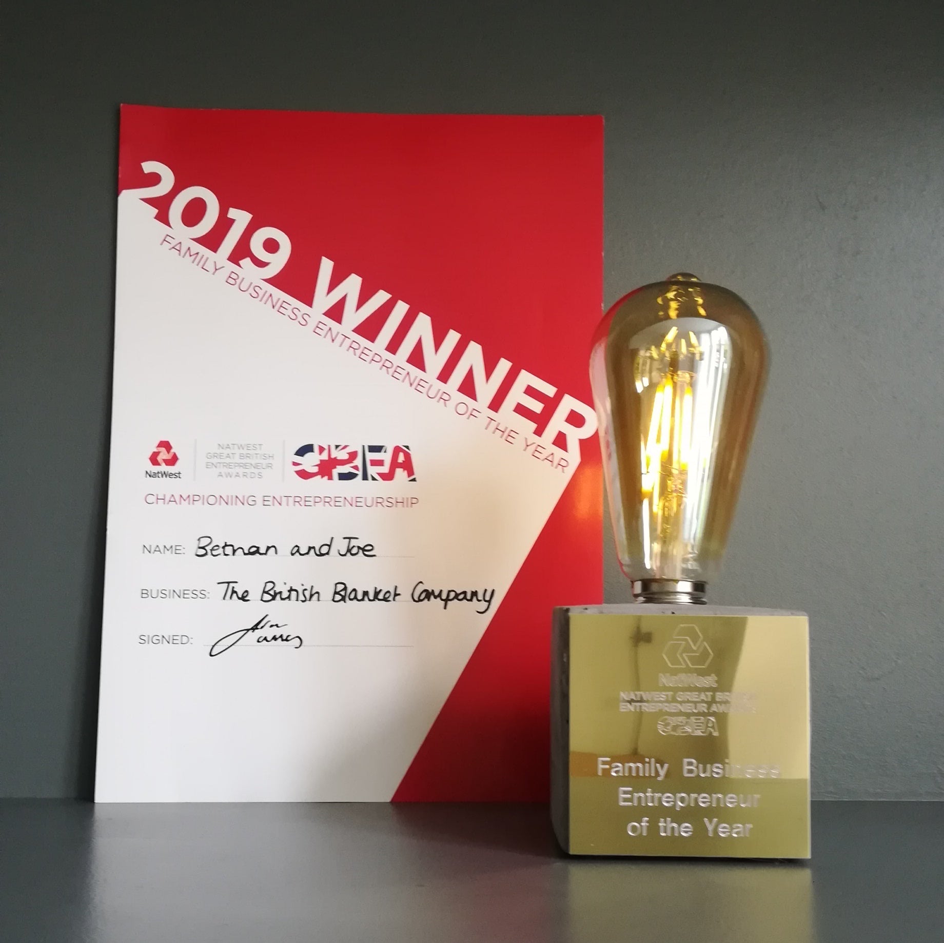 A gold trophy sits prominently on a table, accompanied by a red and white sign with text.