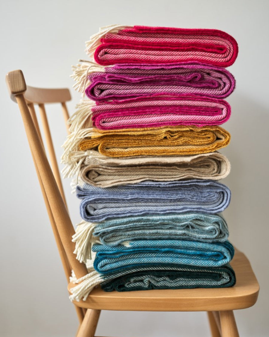 A stack of colorful blankets neatly arranged on a chair, highlighting vibrant textile patterns and fabric textures.