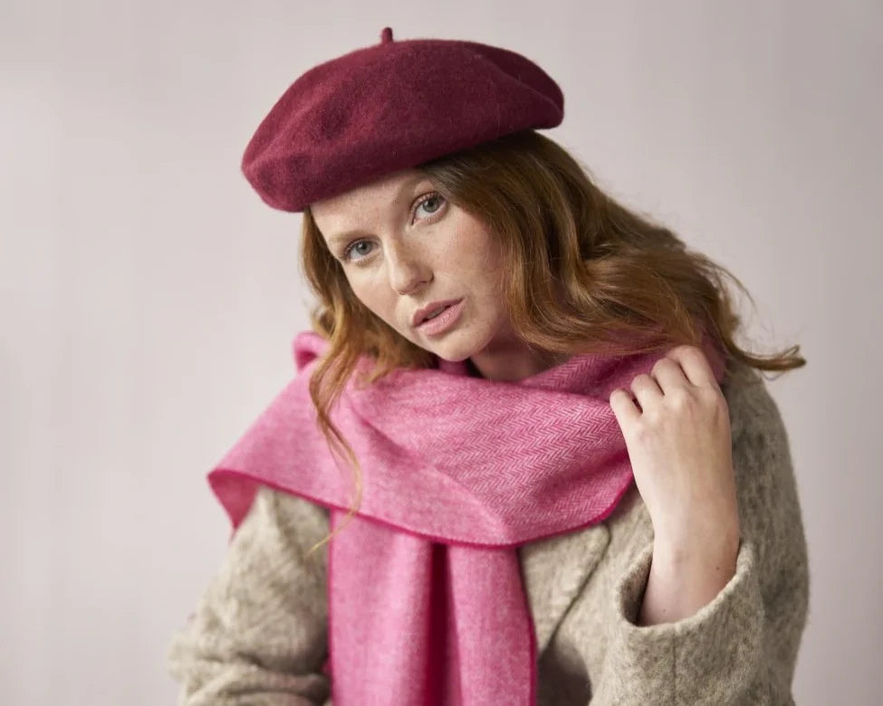 A woman wearing a pink scarf and matching hat, showcasing a cozy fashion accessory in a close-up shot.