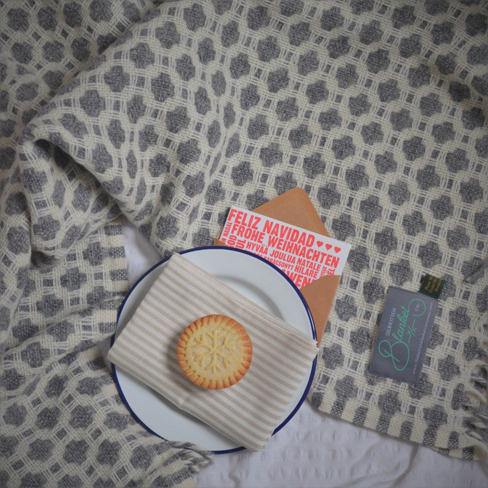 A plate with a cookie and a card, alongside a pie featuring a snowflake design, all arranged on a patterned fabric surface.