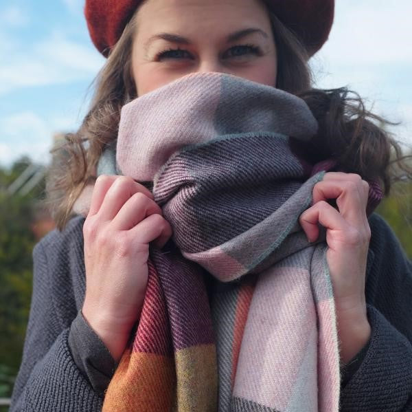 A woman outdoors wearing a hat and scarf, with a close-up focus on her eyes, showcasing fashion accessories in a natural setting.