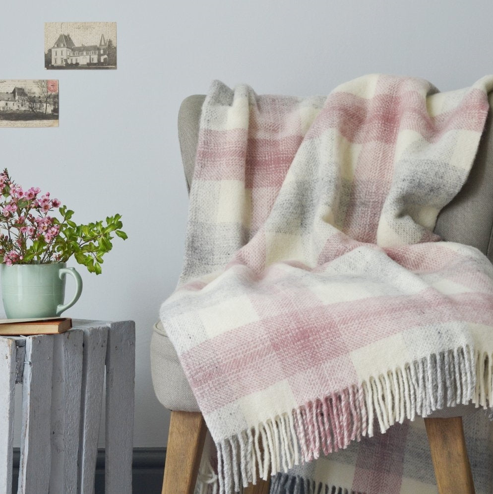 A chair draped with a pink and white plaid blanket, accompanied by a nearby flowerpot and a close-up of a decorative cup.