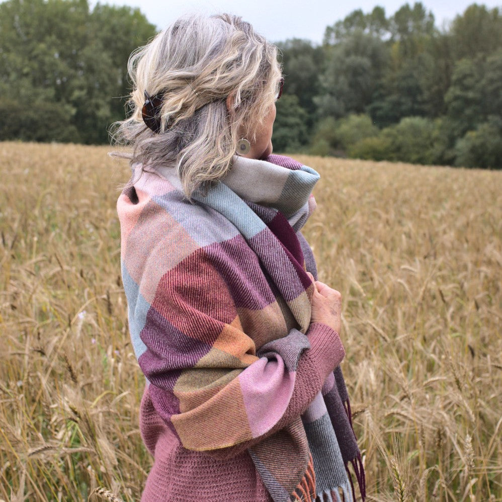A woman in a plaid scarf stands in a wheat field under a clear sky, symbolizing a serene outdoor agricultural scene.