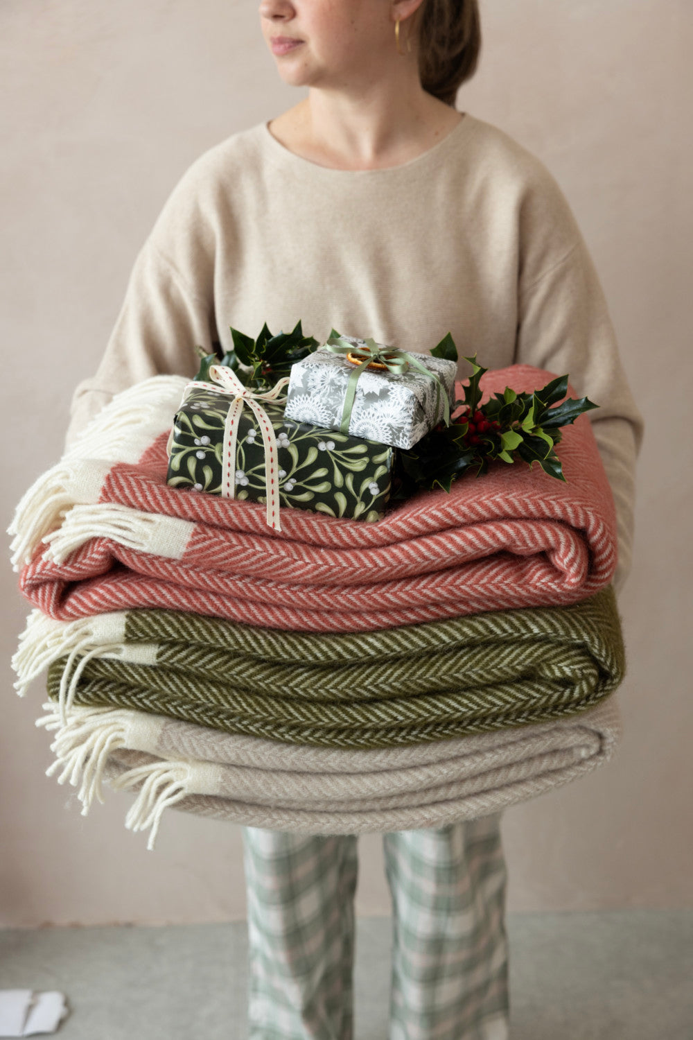 A bed with white linens, a blanket, and a chair holding a cup and a book in a cozy bedroom setting.