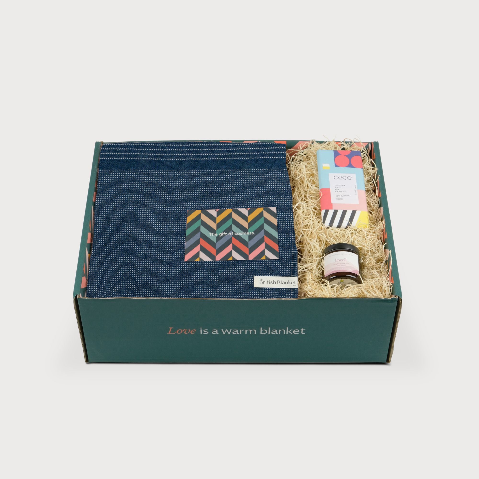 Alpaca Blanket Gift Box: Teal Blue includes a navy blanket, amber jar candle, sea salt chocolate, and gift card, all in eco-friendly packaging.