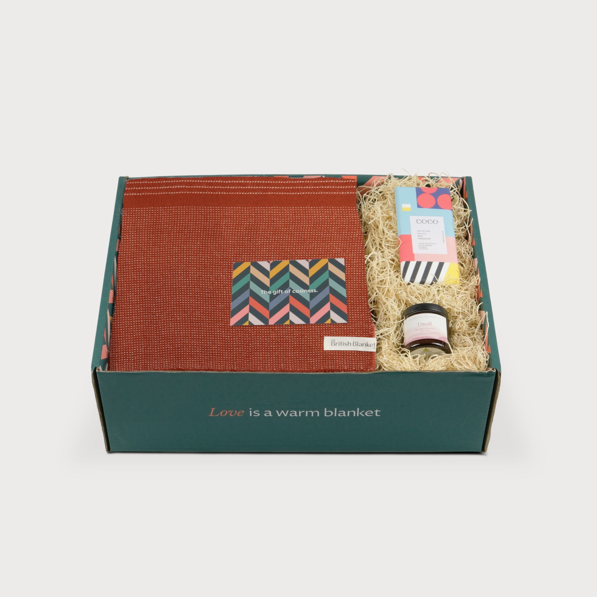 Alpaca Blanket Gift Box: Flame Orange includes a rust-orange blanket, amber candle, sea salt chocolate, card, in a teal box with wood-wool packing.