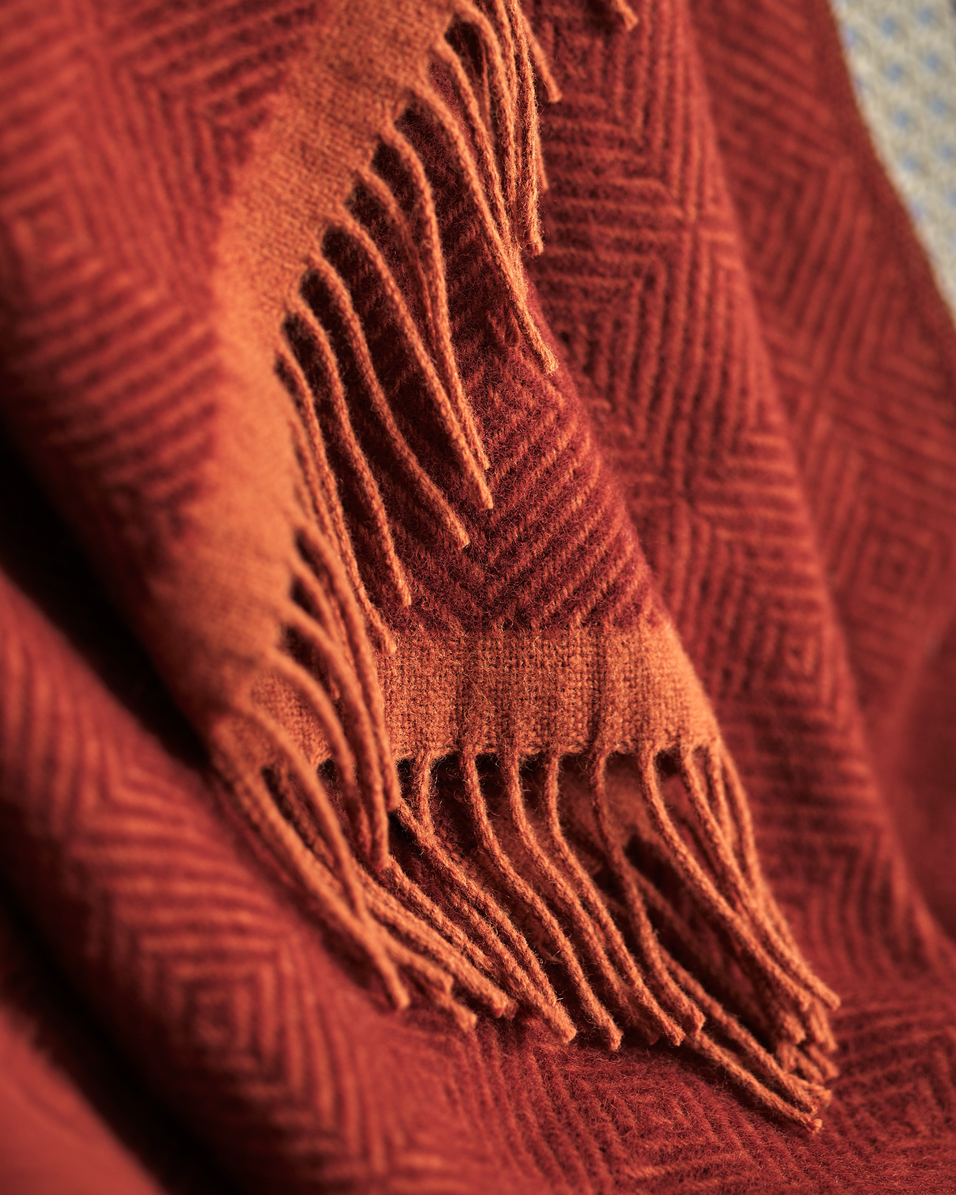 Close-up of the Wildweave Blanket Gift Box: Rowan & Beech, showcasing its rust-colored woven texture, fringed edges, and subtle geometric pattern for a cozy home experience.