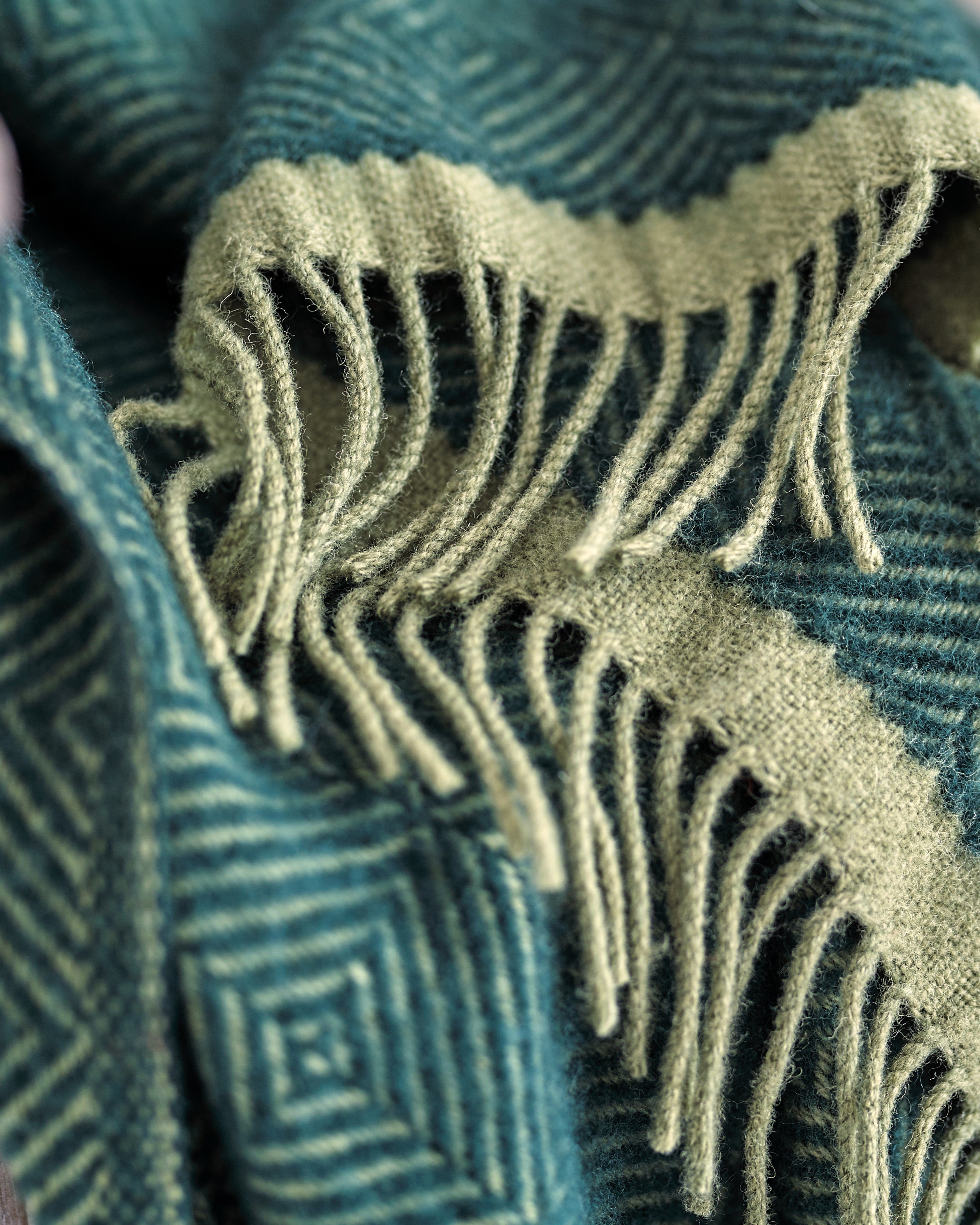 Wildweave Blanket Gift Box: Juniper & Moss, showcasing a wool blanket with geometric patterns and fringe, part of a cozy gift set including chocolate and candle.