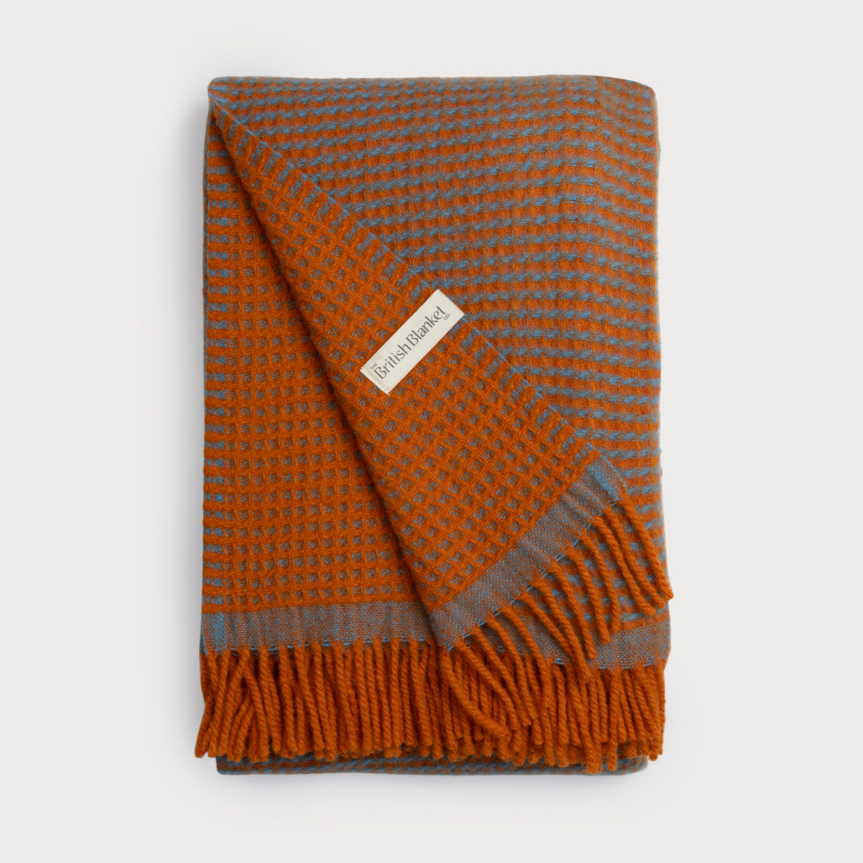 Totterdown Waffle Blanket: Beacon & Lido, folded, showcasing its textured, reversible waffle weave with fringed edges and a visible logo tag.