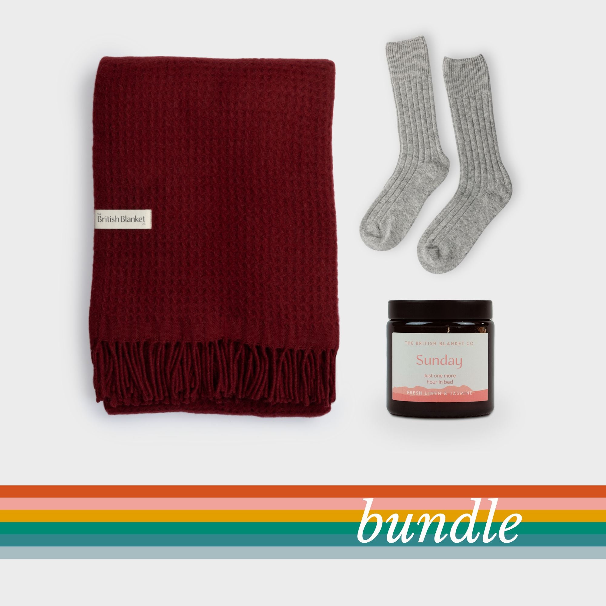 Bright Friday Blanket Bundle: Air Balloon includes a burgundy waffle-weave throw, heather-grey ribbed socks, and an amber-glass candle with a fresh linen and jasmine scent.