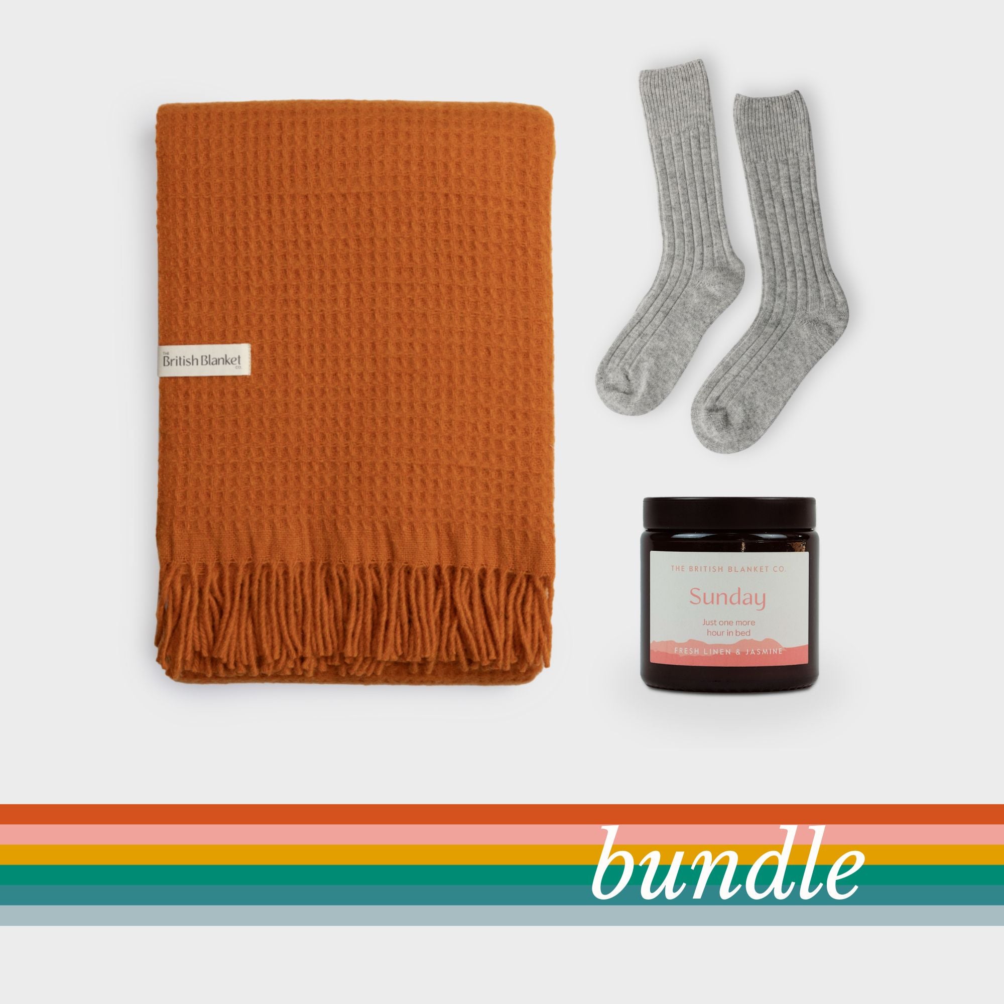 Bright Friday Blanket Bundle: Beacon features a burnt-orange waffle blanket, grey knit socks, and an amber candle labeled “Sunday” on a neutral backdrop.