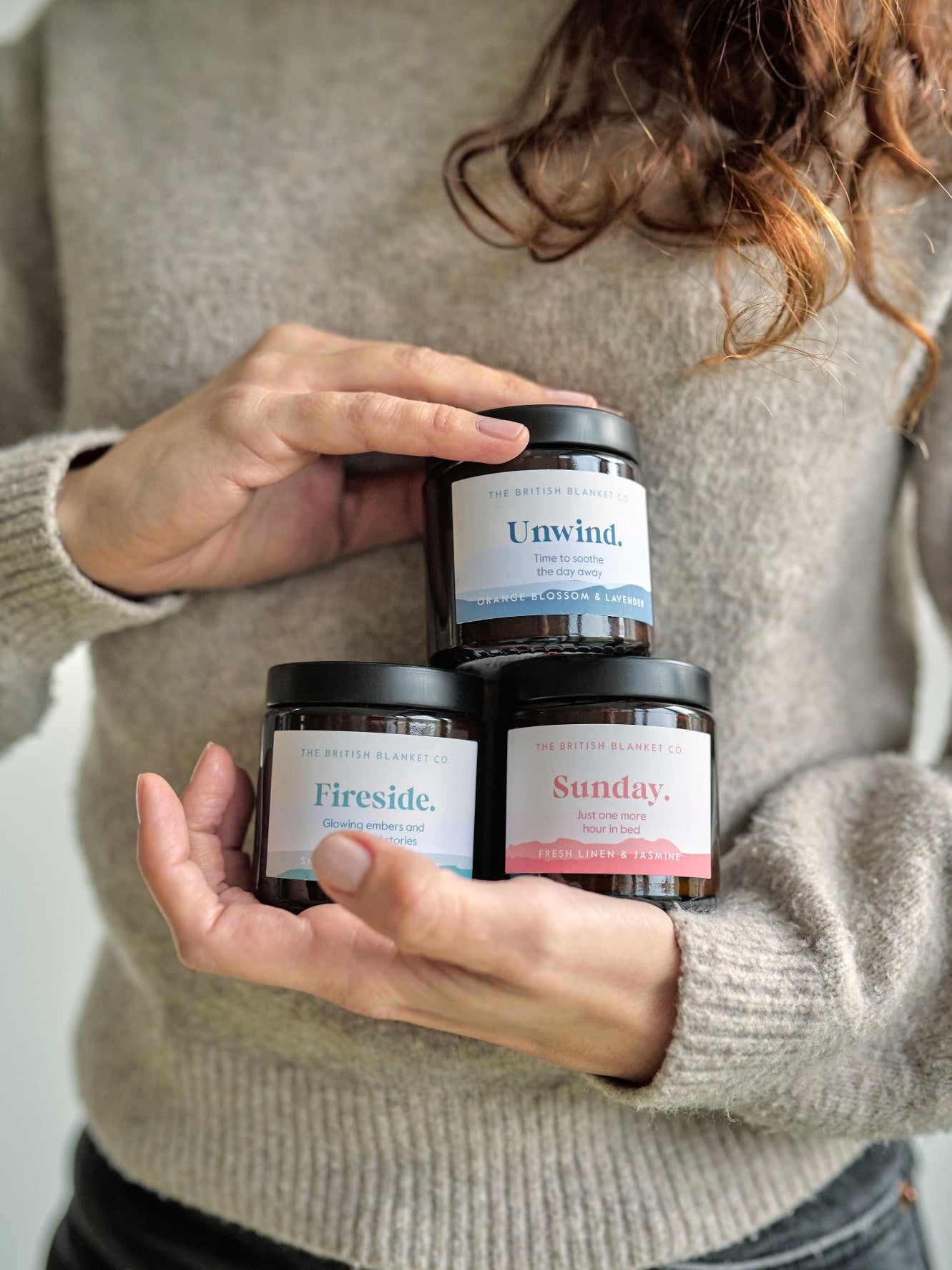 Amber Jar Candle by The British Blanket Co. held by a woman, showcasing its compact size and elegant design. Perfect for creating a cozy, aromatic atmosphere.