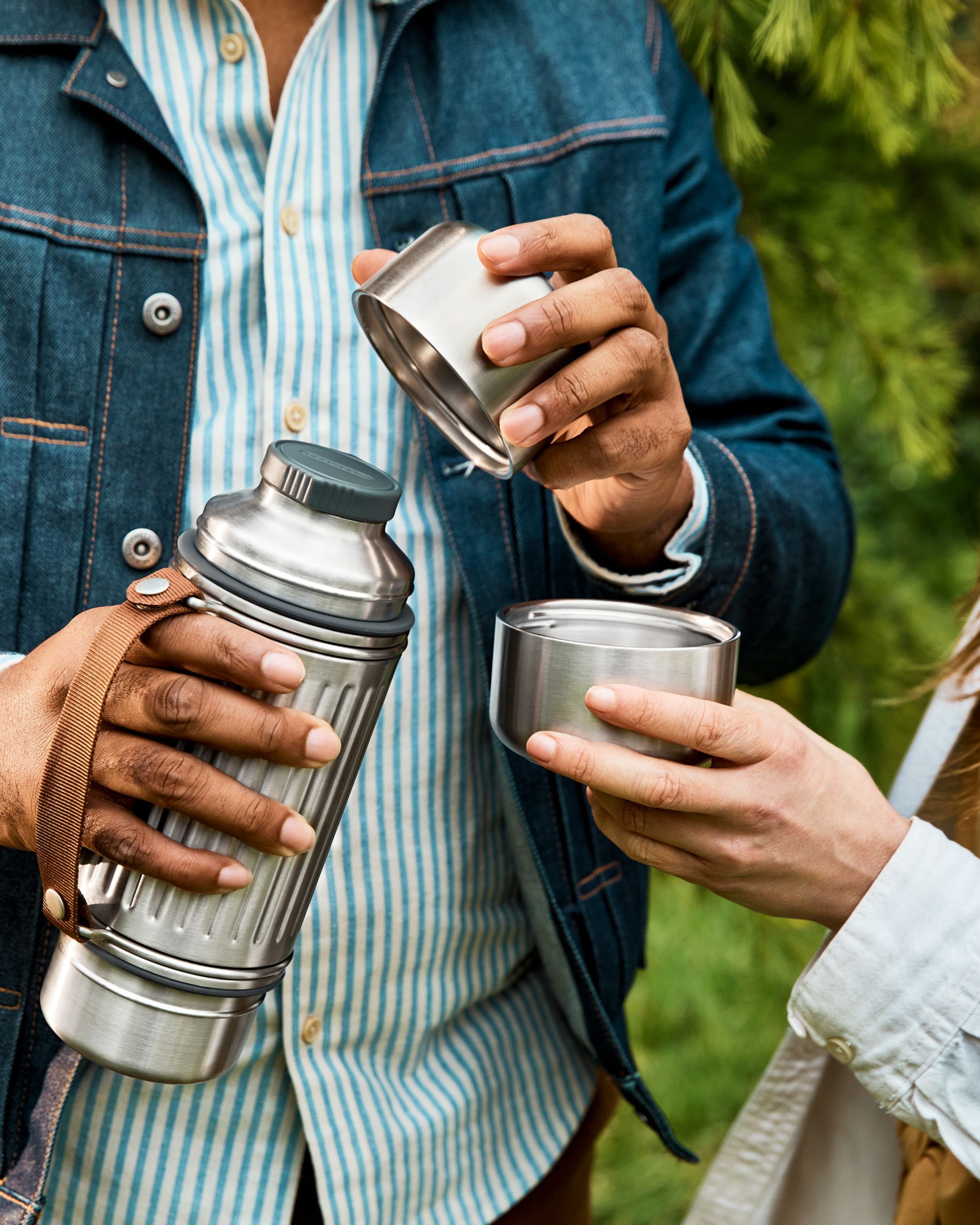 Two people using the Black + Blum Stainless Steel Flask, with two detachable cups