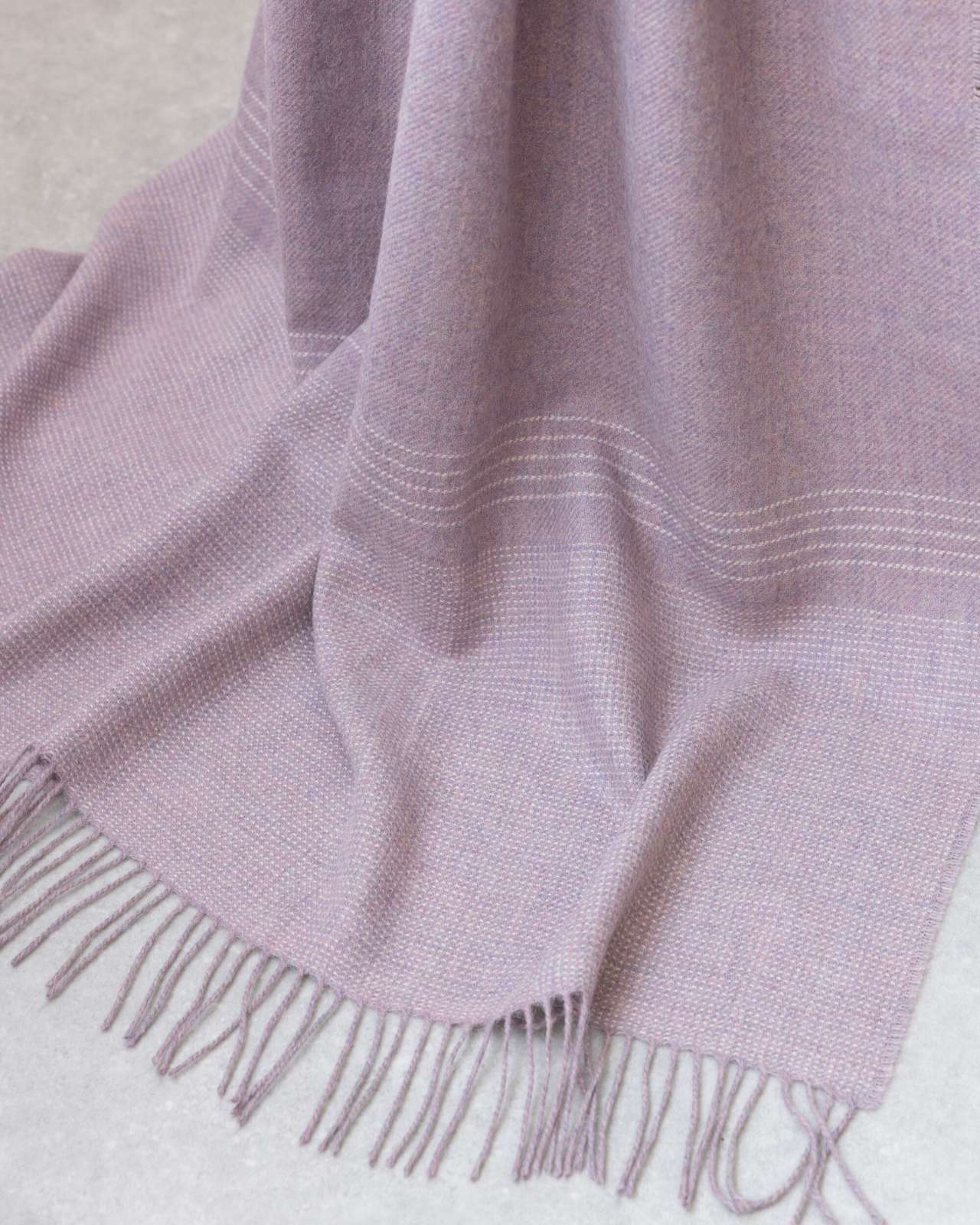 Heather Pink Alpaca Blanket, featuring soft woven texture with fringe tassels, elegantly draped. Part of the Alpaca Blanket Gift Box with candle and chocolate.