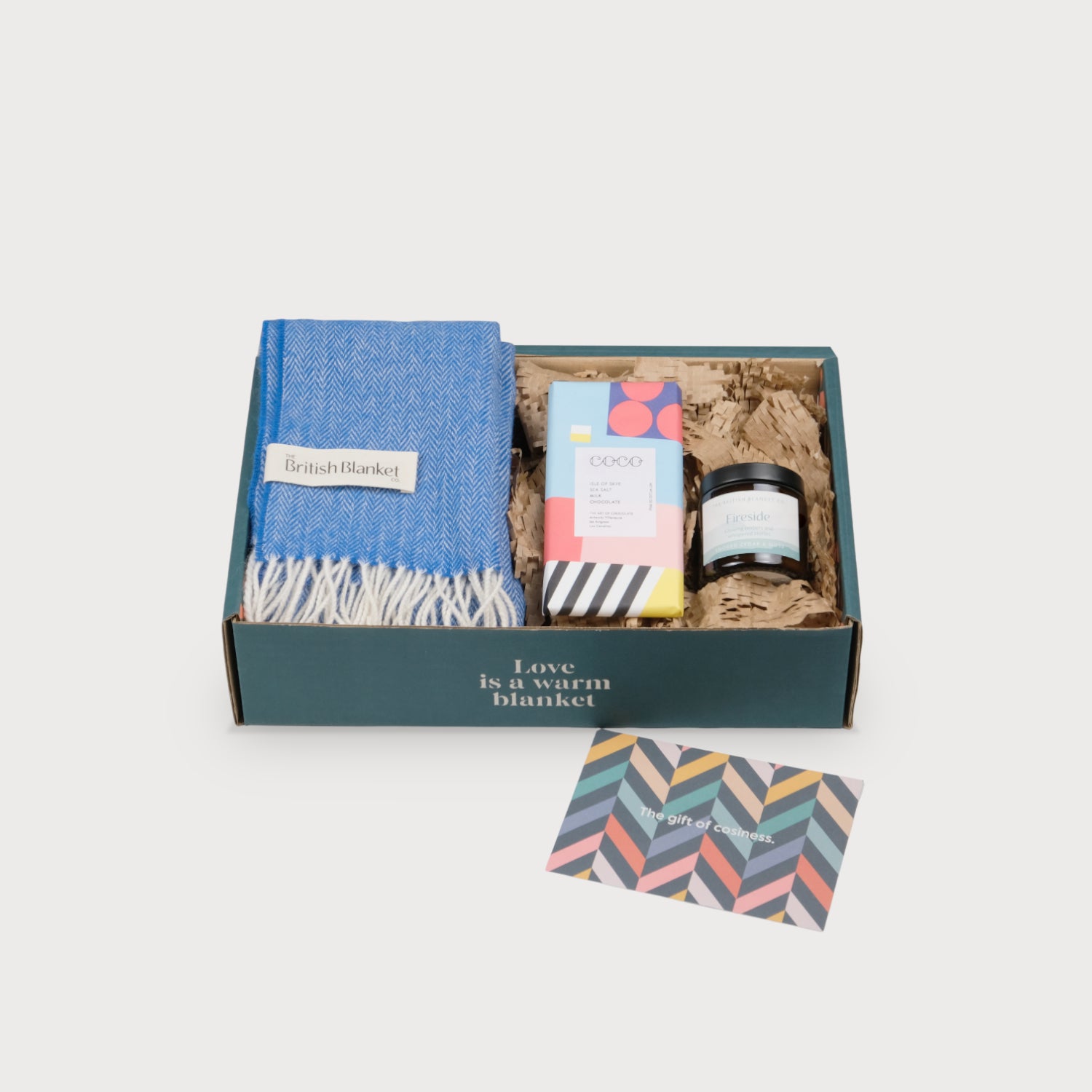 Herringbone Scarf Gift Box: Cobalt Herringbone includes a folded wool throw, artisan chocolate, a Fireside candle, and a chevron-patterned gift card in a mailer box.