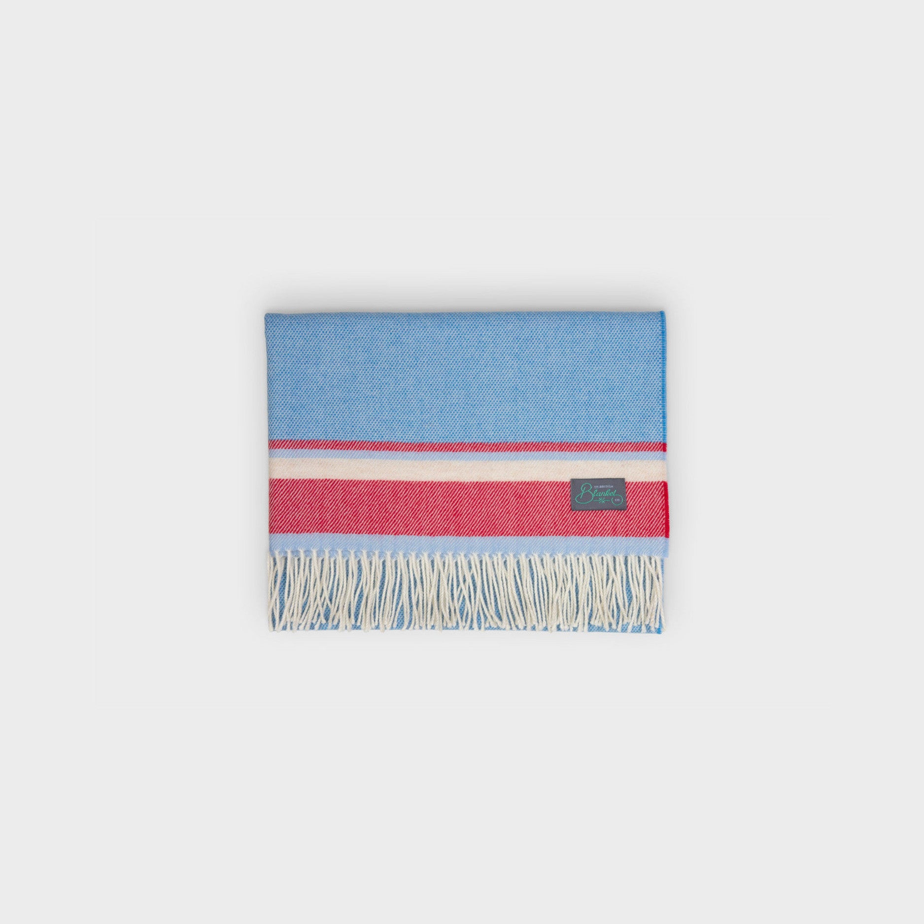 Baby Blanket Hamper featuring a folded woven throw with a stripe and fringe, accompanied by a crochet sheep rattle in a gift box.