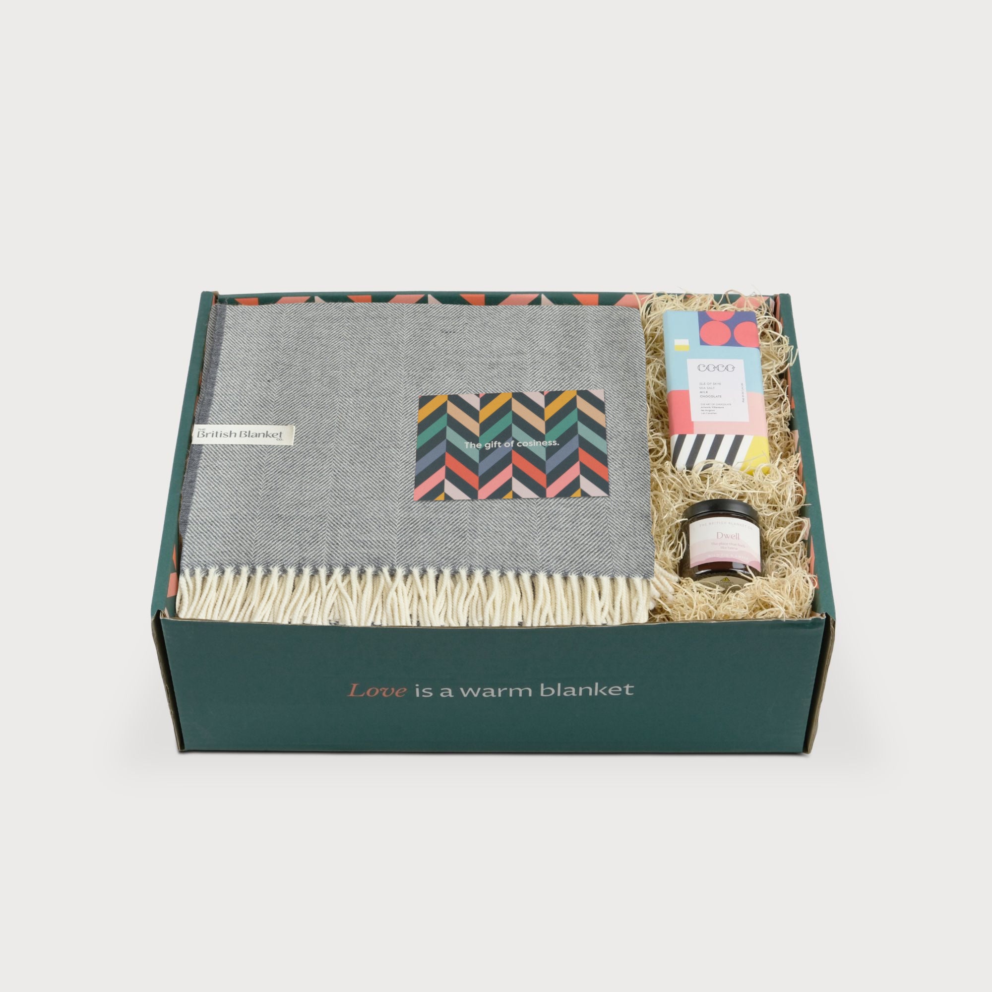 Merino Blanket Gift Box: Uniform Grey, includes a herringbone throw, greeting card, Coco chocolate, and Dwell candle, all arranged in a gift box.