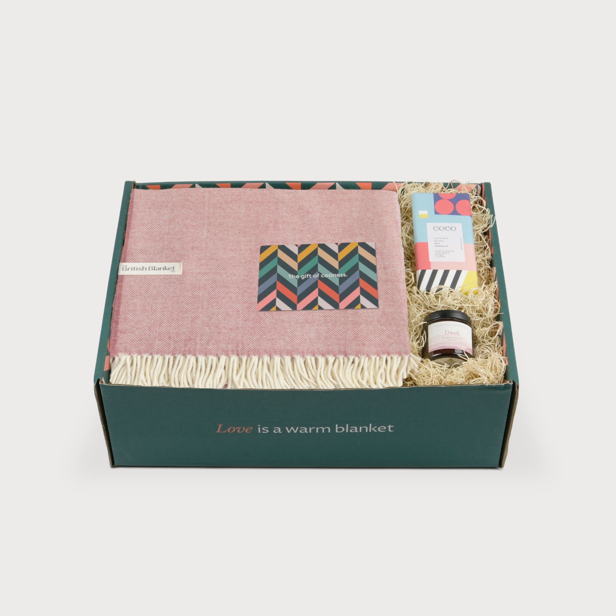 Merino Blanket Gift Box: Blush Pink includes a soft throw, sea salt chocolate, candle, and greeting card, elegantly arranged inside a gift box.