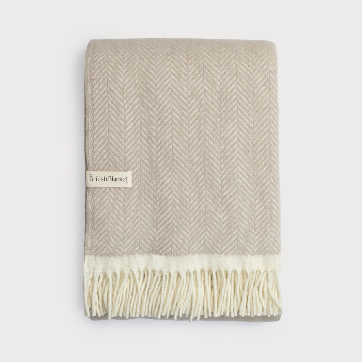 The Christmas Blanket Gift Box: Bath Stone features a folded throw with a beige-and-cream herringbone pattern and cream fringe, labeled British Blanket Co.