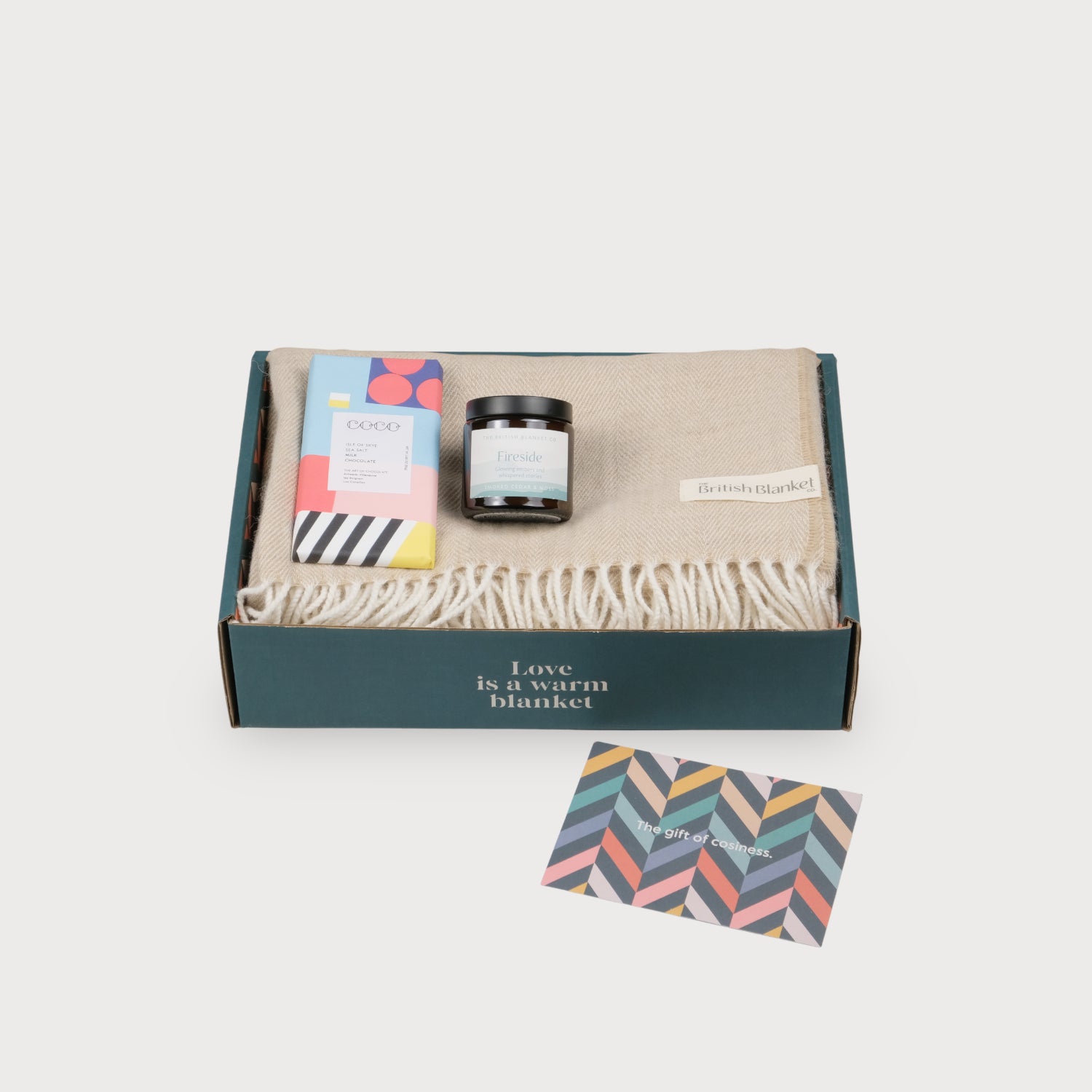 Oversized Blanket Scarf Gift Box: Basswood Herringbone features a merino lambswool scarf, Fireside candle, COCO chocolate bar, and gift card in a dark teal box.