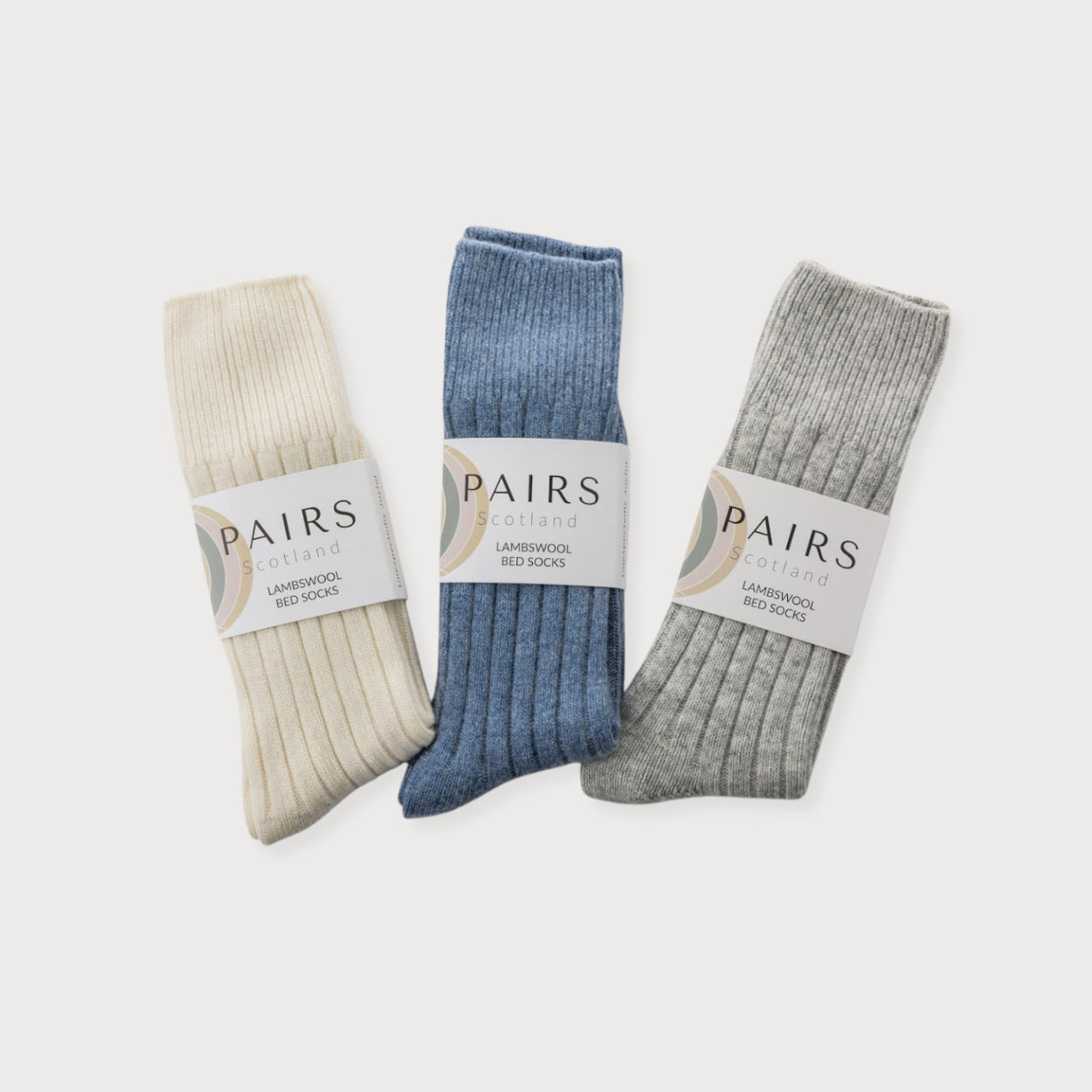 Cosy Gift Set: Feet Up features three pairs of ribbed lambswool bed socks, each wrapped with PAIRS Scotland paper bands, perfect for a thoughtful gift.
