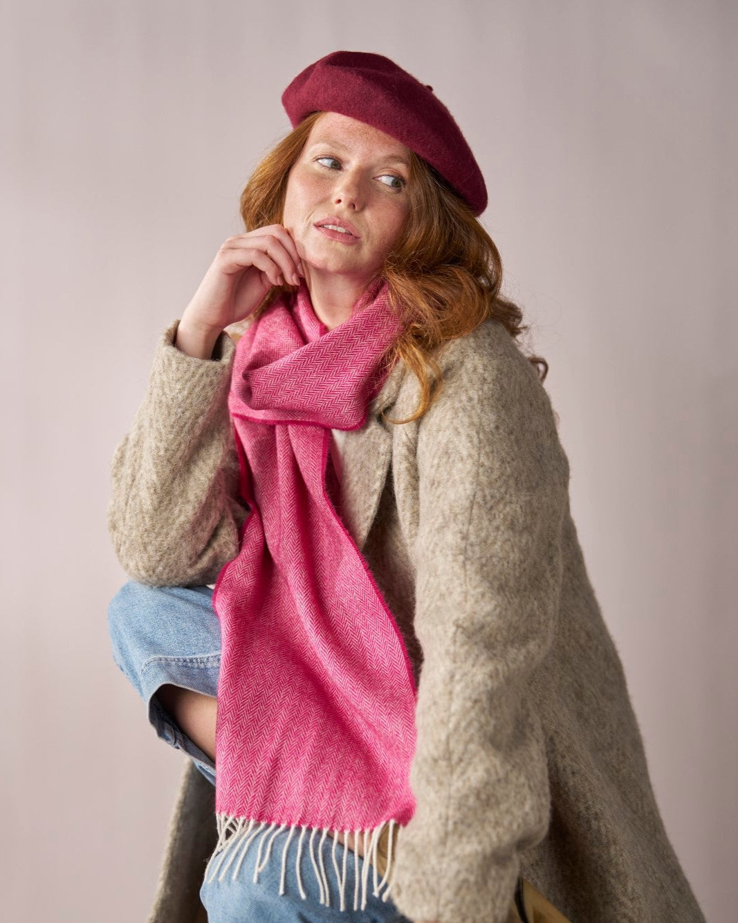Person wearing a Burgundy Wool Beret Hat, showcasing its thick felt texture and structured shape, paired with a pink textured scarf and oatmeal coat.