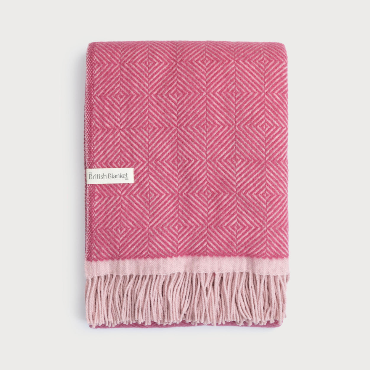 Wildweave Blanket Gift Box: Clover & Briar Rose features a folded pink throw with a diamond pattern, fringe, and The British Blanket Co. label.