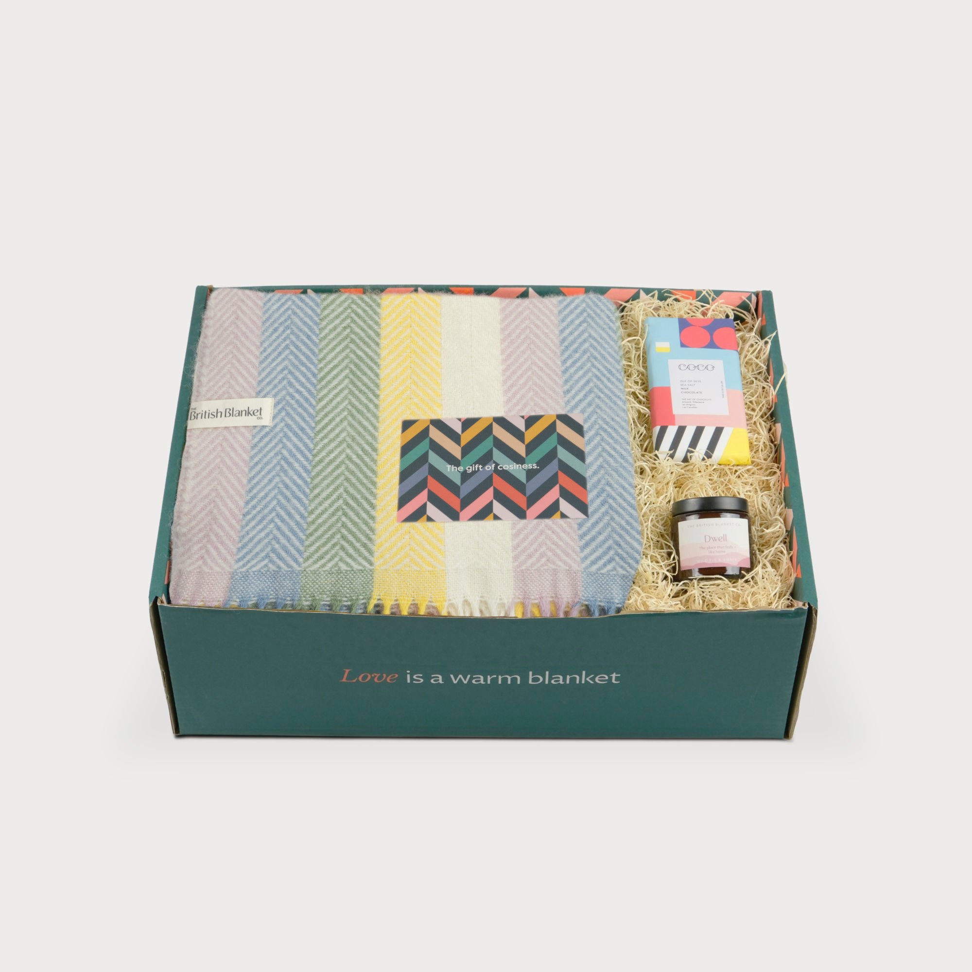 Rainbow Stripe Blanket Gift Box: Pastel, featuring a wool blanket, chocolate bar, preserve jar, and gift card, all nestled in shredded paper within a labeled box.