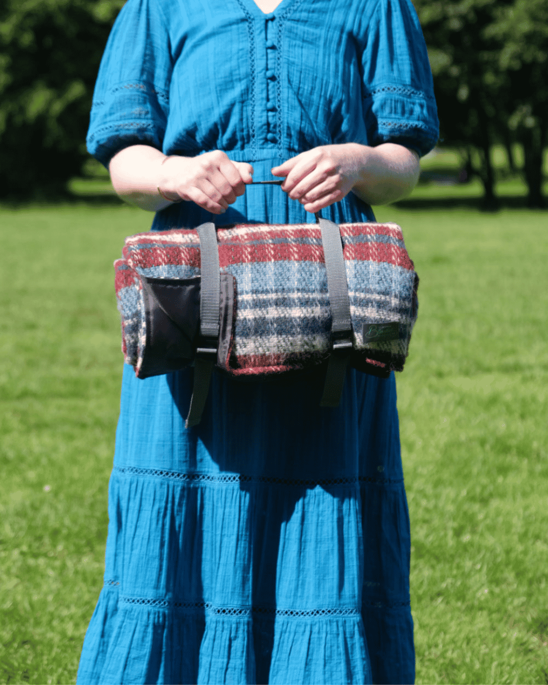 Person holding waterproof backed Random Picnic Blanket with carry strap