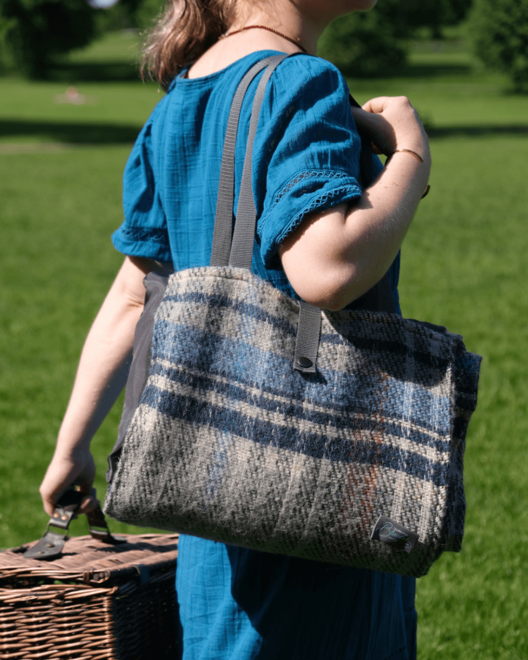 Bethan holding a waterproof picnic blanket neatly folded with a long shoulder strap