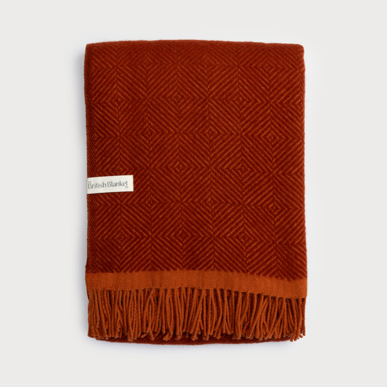 Wildweave Blanket Gift Box: Rowan & Beech features a burnt-orange wool blanket with a geometric weave and fringe, labeled “British Blanket Co.”