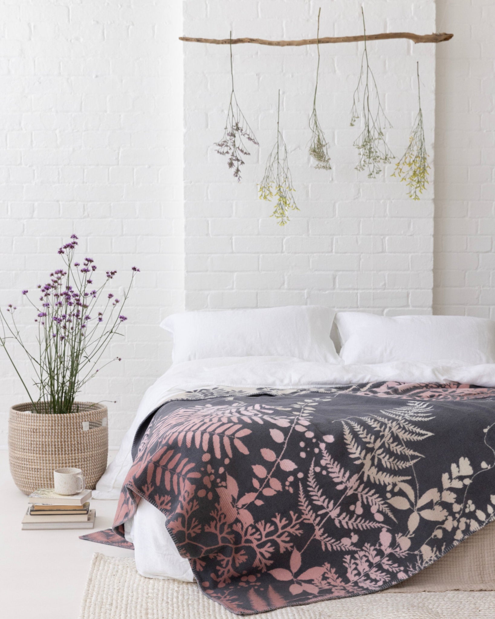Clarissa Hulse Blanket: Kaleidoscope in Shell drapes the bed, featuring soft pink and cream fern motifs, complementing the minimalist bedroom's serene, organic aesthetic.