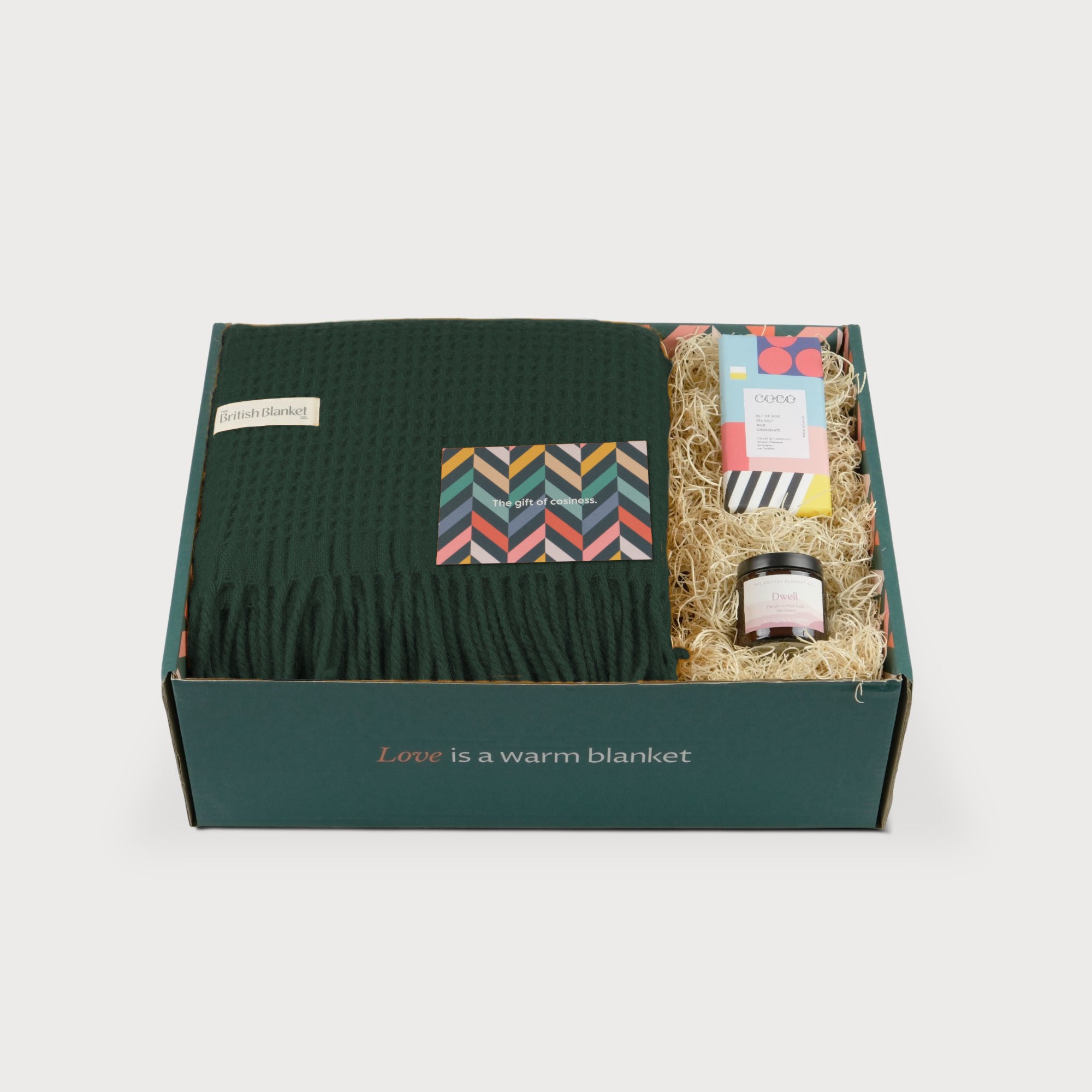 Totterdown Blanket Gift Box: College Green features a dark-green waffle blanket, chevron gift card, Coco chocolate bar, and Dwell candle, nestled in straw paper.