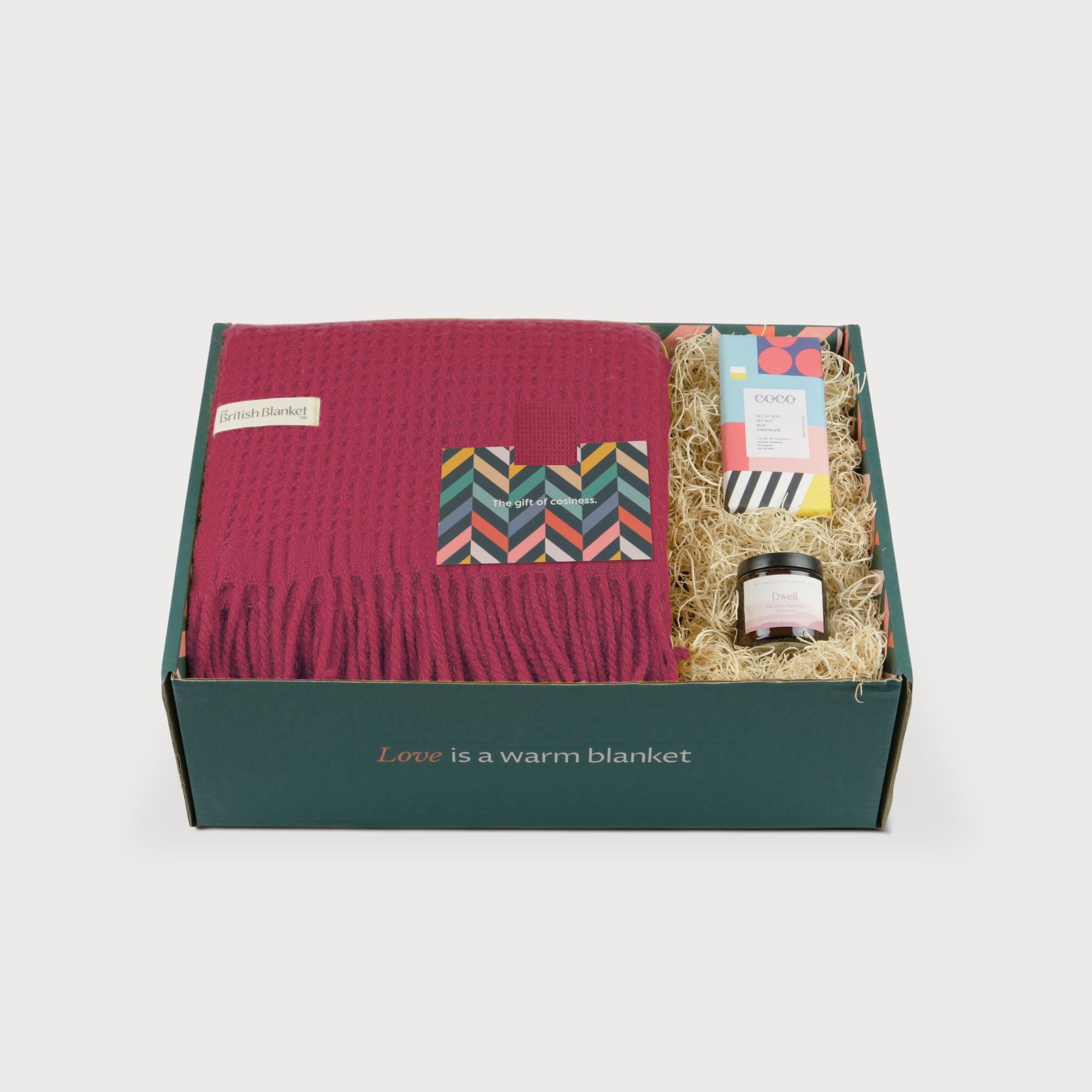 Totterdown Blanket Gift Box: Lush features a raspberry-red blanket, COCO chocolate, Dwell jar, and greeting card, all nestled in a green box.