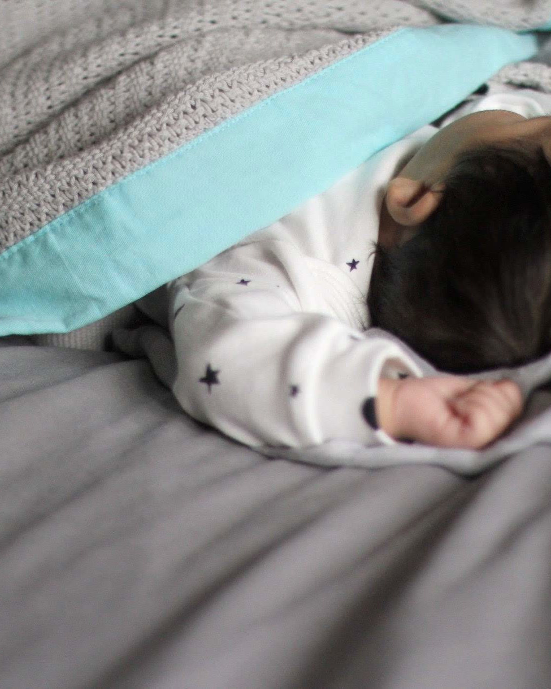 Baby peacefully sleeping under the Organic Cotton Cellular Baby Blanket: Turquoise, showcasing its breathable, lightweight design, ideal for regulating temperature.