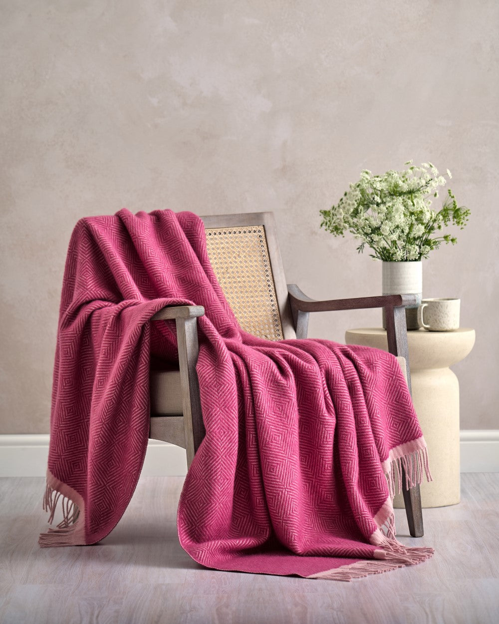 Wildweave Blanket Gift Box: Clover & Briar Rose; mid-century chair with pink throw, side table with mug, vase, and flowers, creating a cozy indoor scene.