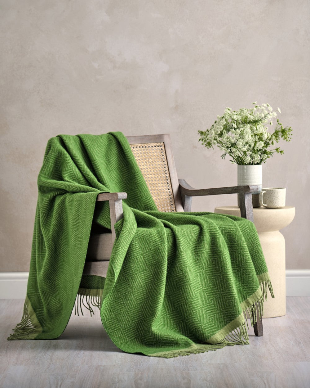 Wildweave Blanket Gift Box: Fennel & Catkin features a cozy wooden armchair with a draped green blanket, side table with blooms, and ceramic mug.