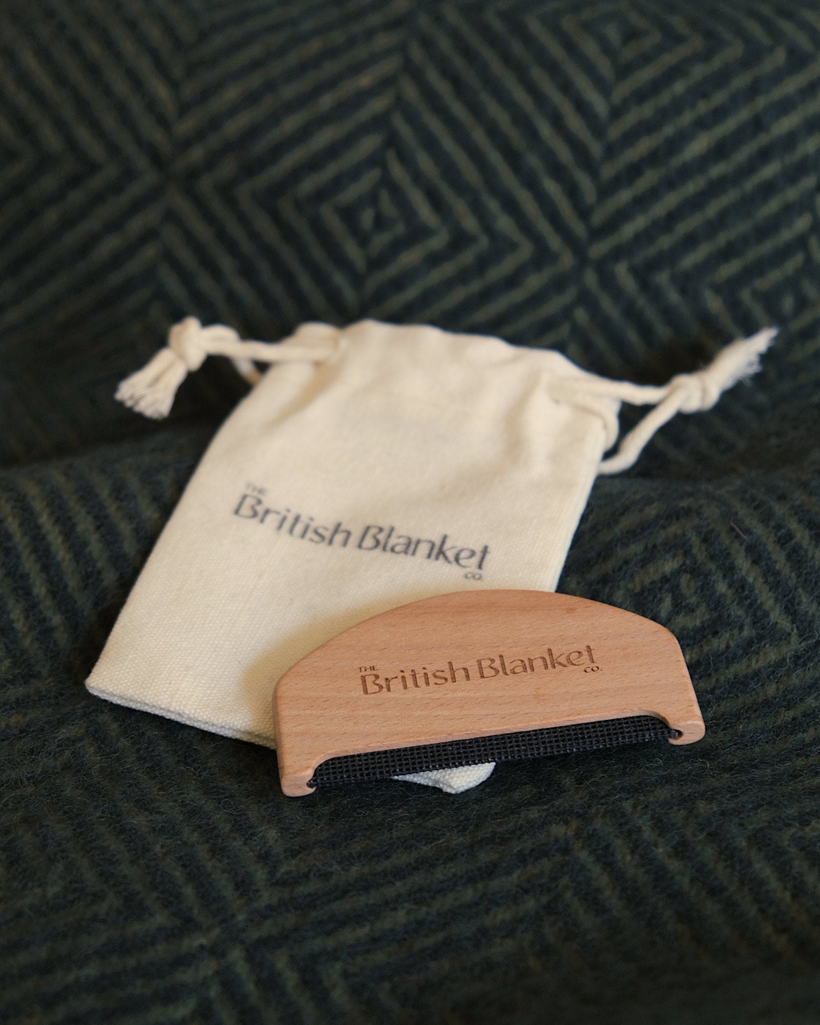 Beech wood Wool Care Comb beside its cotton storage bag, designed for gently removing pilling from woollen blankets and garments.