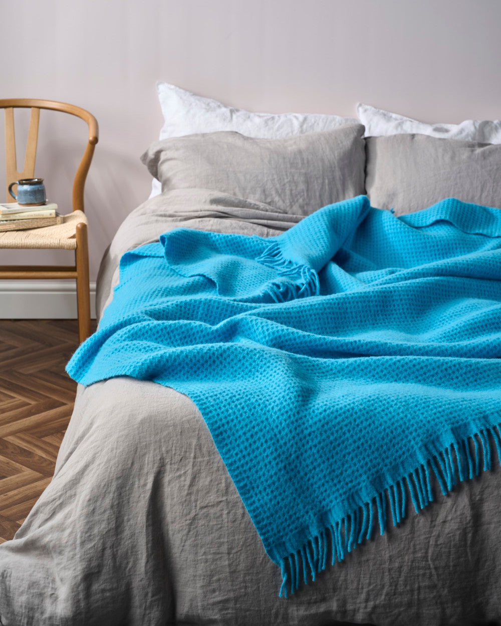 Bright Friday Blanket Bundle: Lido draped on a bed, showcasing its woven texture and fringe, complementing the soft linen sheets and cozy room setting.