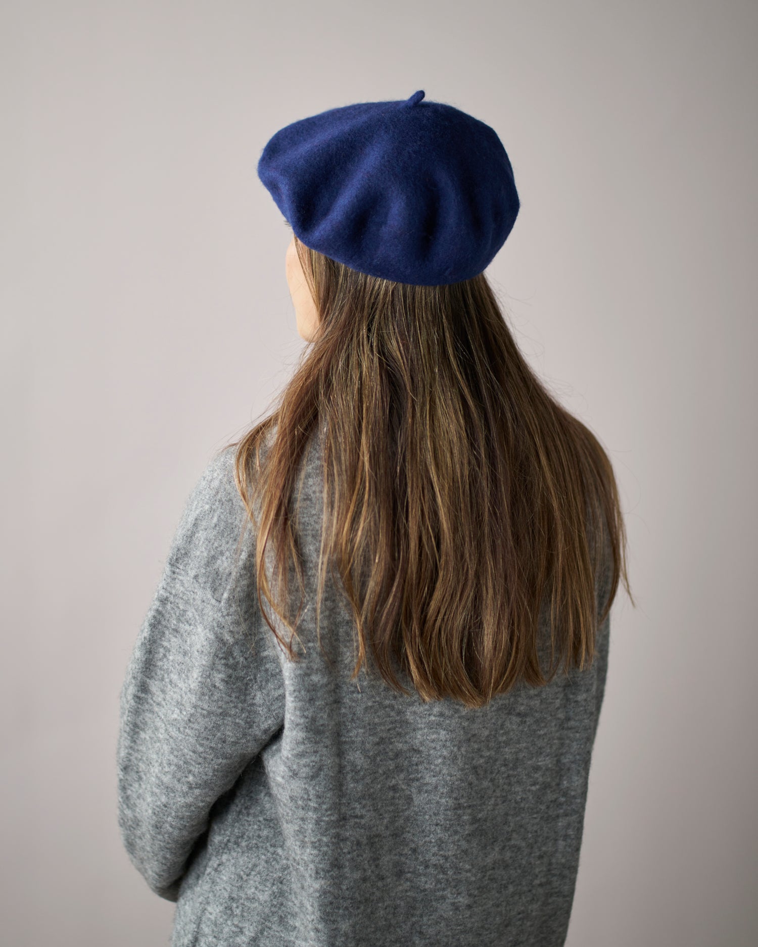 Wool Beret Hat: Navy Blue, shown on a person with long brown hair, offering a timeless, structured look against a neutral background.