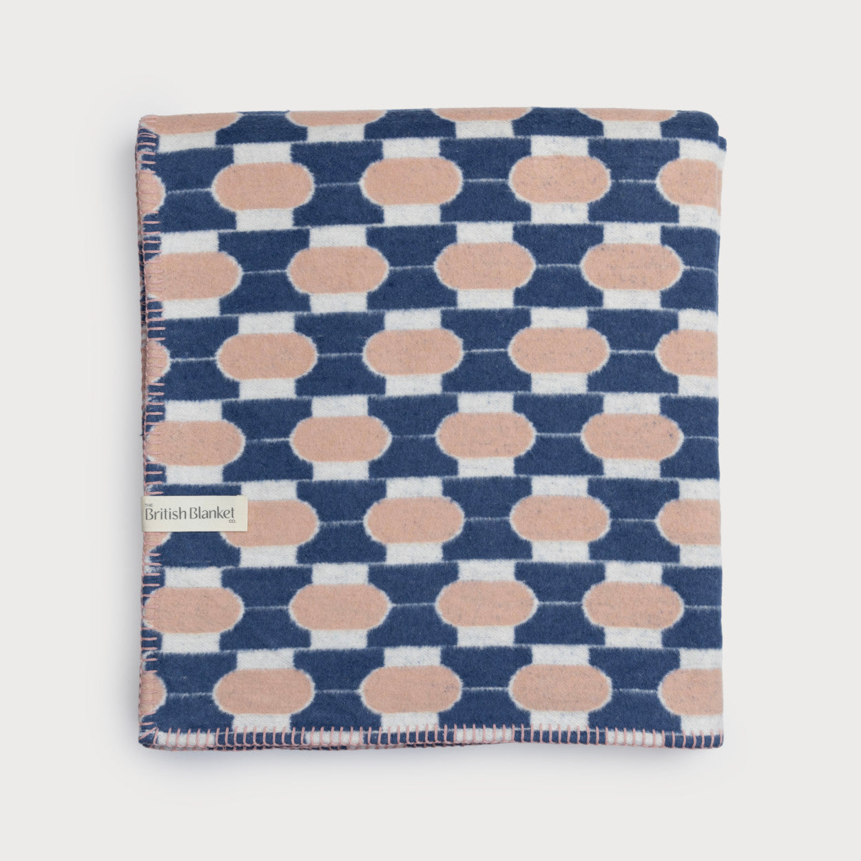 Cloud Cotton Blanket: Boatyard Shell (C) with a midcentury geometric pattern, whip-stitched edge, and British Blanket Co. label, showcasing its soft, eco-friendly design.