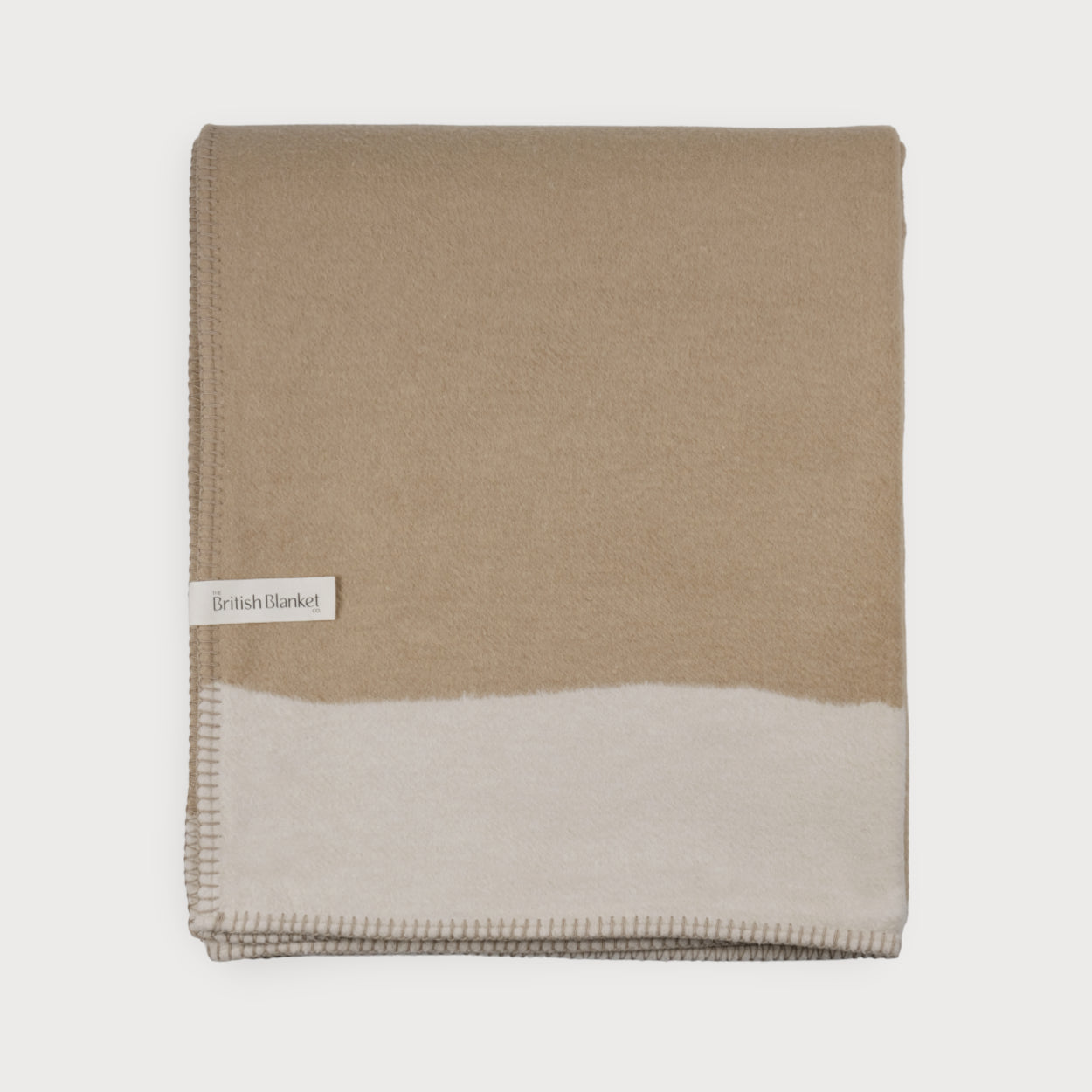 Cloud Cotton Blanket: Strata in Clay—folded two-tone throw with stitched edges, featuring a reversible design and a tag from British Blanket Co.