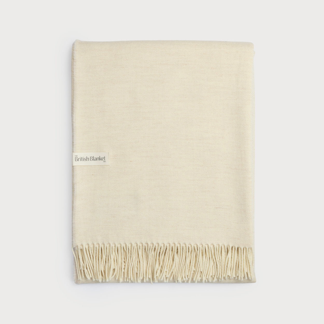 Merino Blanket Gift Box: Cream, featuring a neatly folded ivory-cream wool blanket with fringe, showcasing The British Blanket Co. label, ideal for gifting.