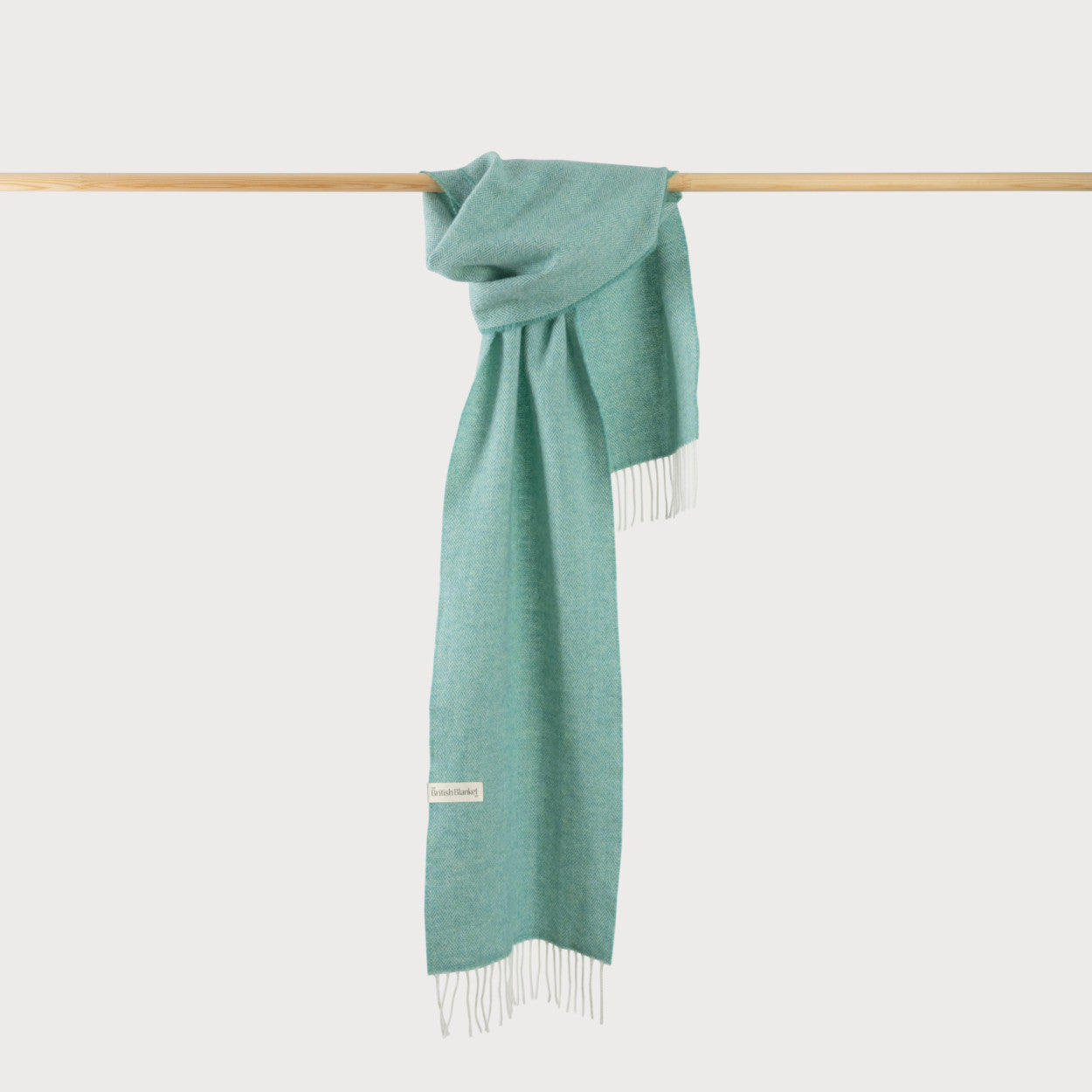 Herringbone Scarf: Spearmint, draped over a wooden bar, showcasing its fine weave and luxurious texture.