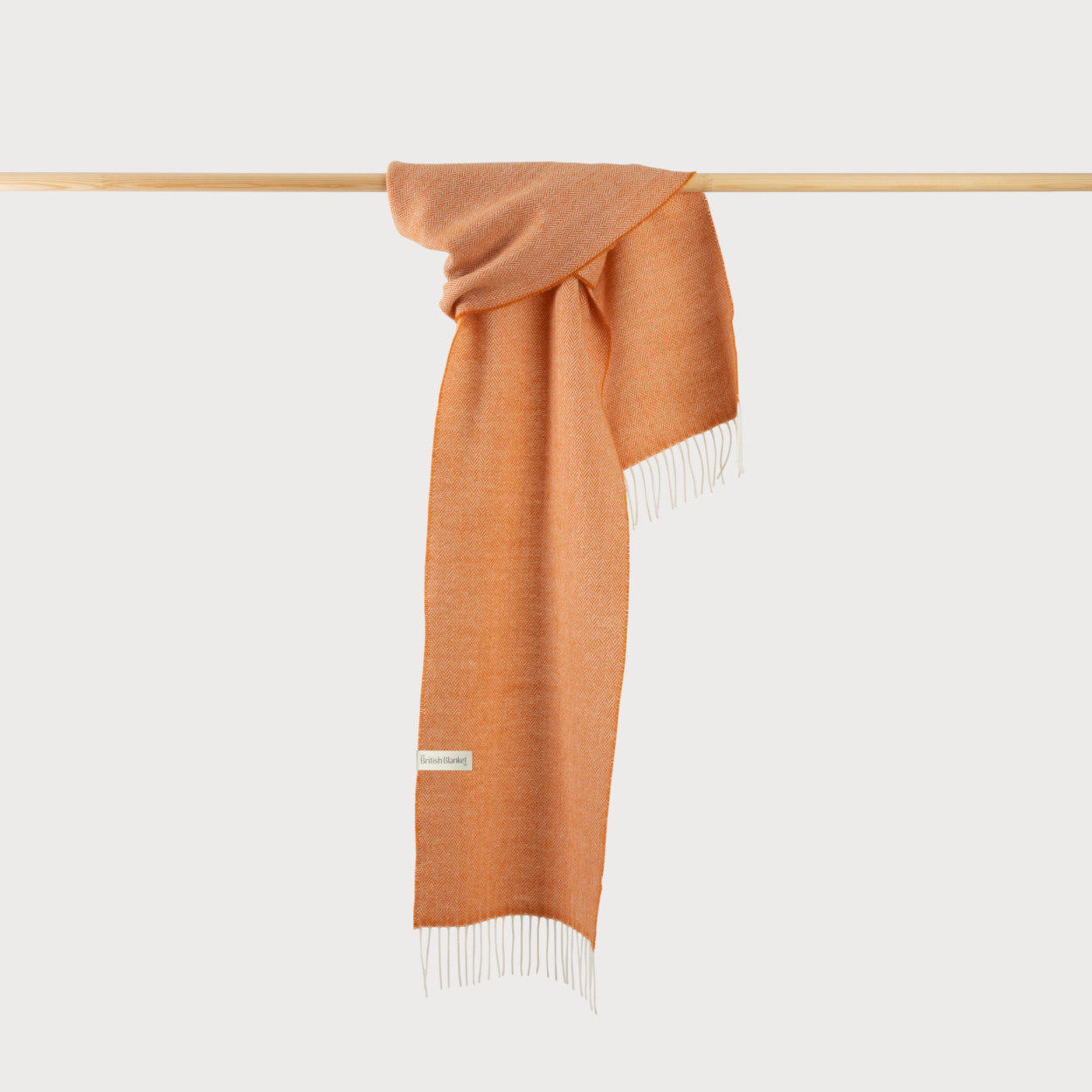 Herringbone Scarf: Mandarin displayed on a wooden bar, showcasing its intricate weave and soft texture.