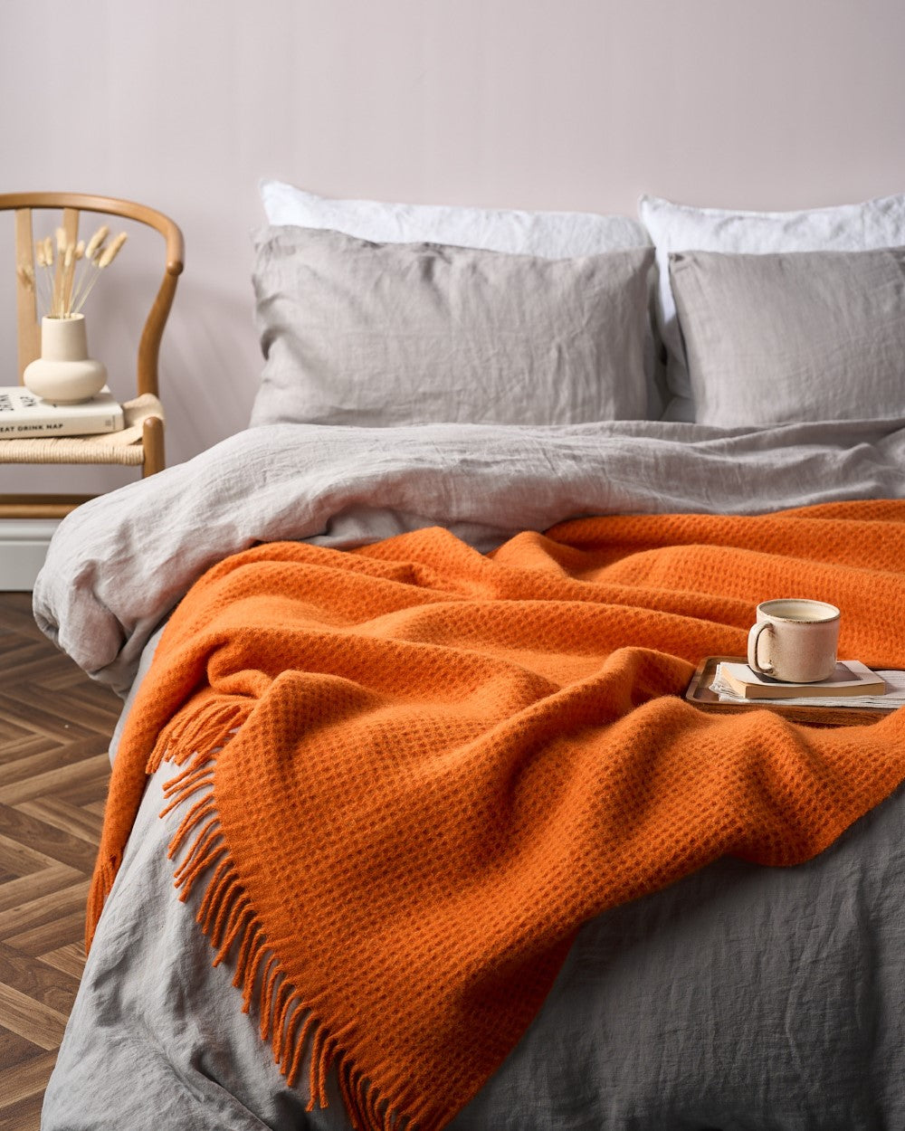 A textured throw blanket with fringe from the Bright Friday Blanket Bundle: Beacon elegantly drapes across a bed, accompanied by a tray, mug, and books.
