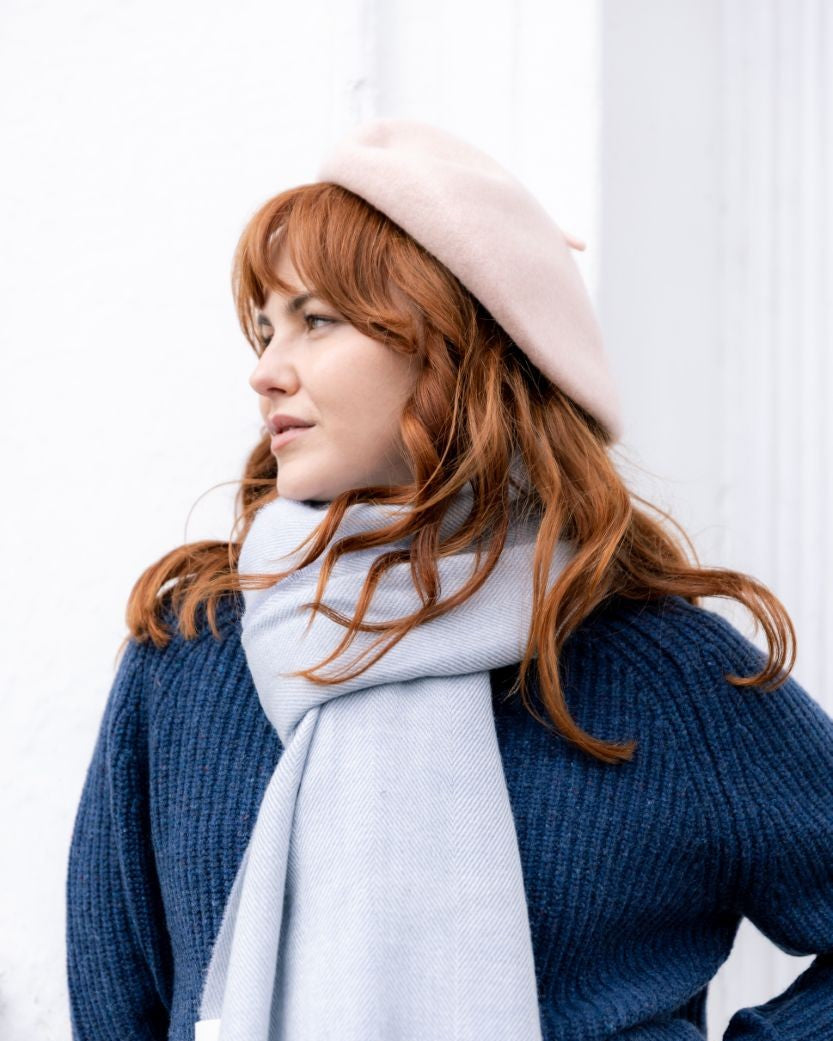 Woman wearing Wool Beret Hat: Baby Pink, made of 100% wool, showcasing premium thickness and French chic style, paired with a light-gray scarf and navy-blue sweater.