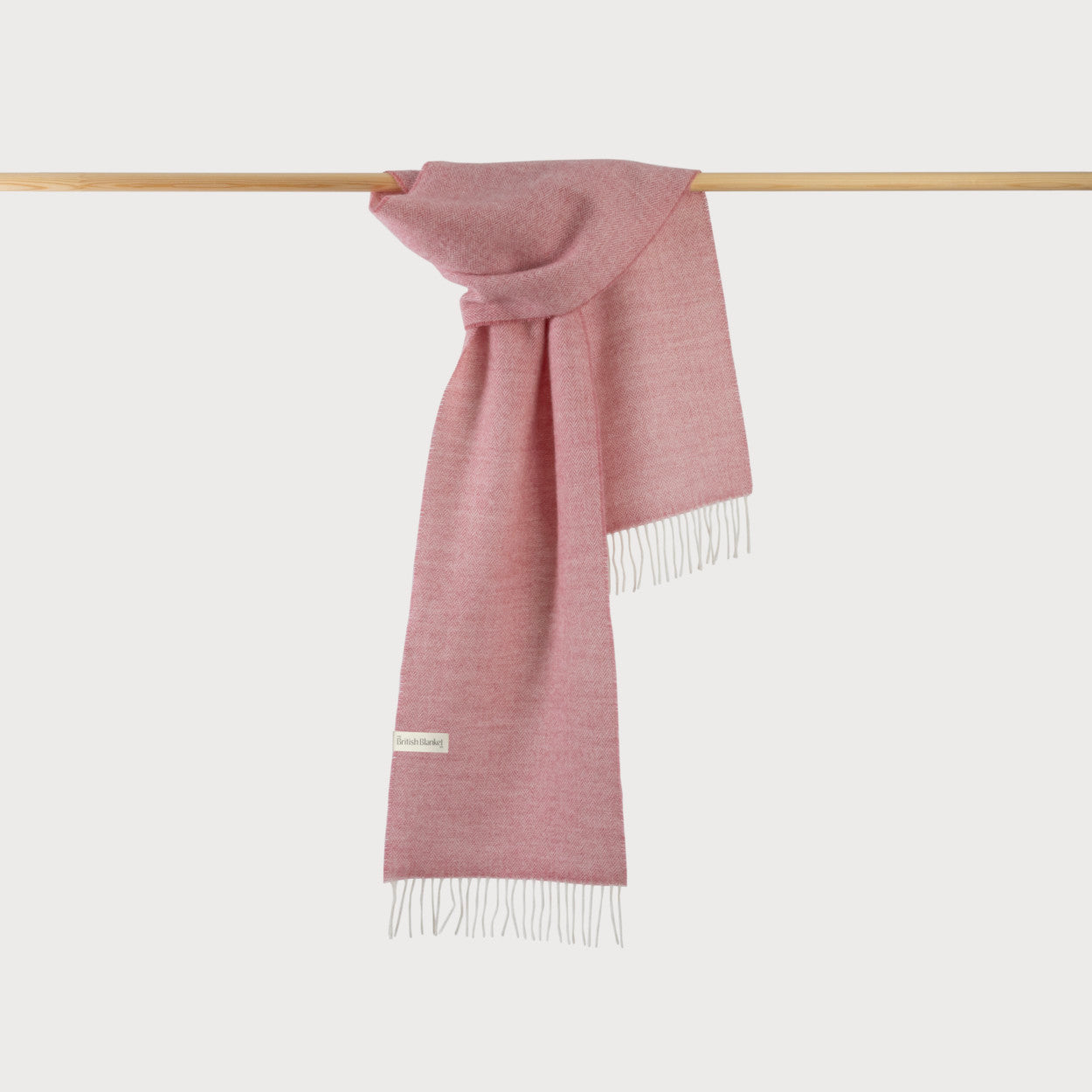 Scarf Gift Box: Blossom Herringbone—soft pink woven scarf with fringe, elegantly draped, highlighting its merino wool texture, perfect for adding warmth and color.